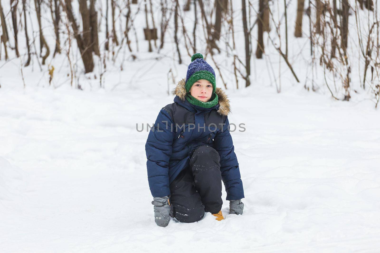 Cute young boy plays with snow, have fun, smiles. Teenager in winter park. Active lifestyle, winter activity, outdoor winter games, snowballs. by Satura86