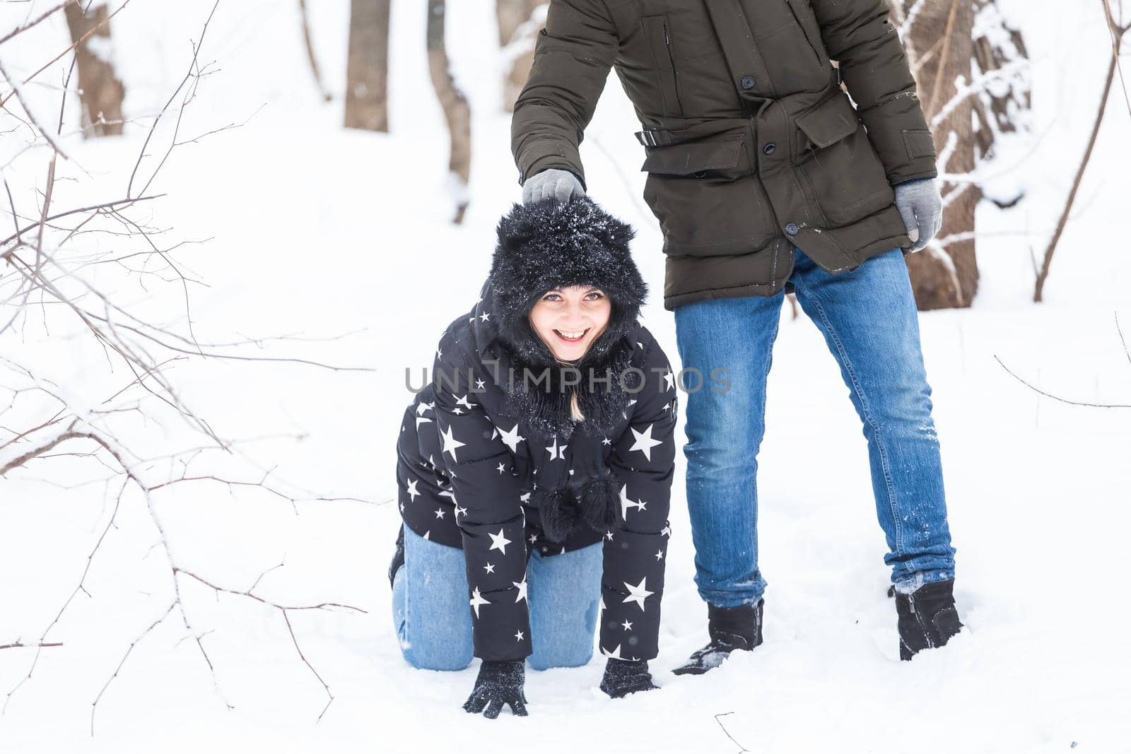 Fun, season and leisure concept - love couple plays winter wood on snow.