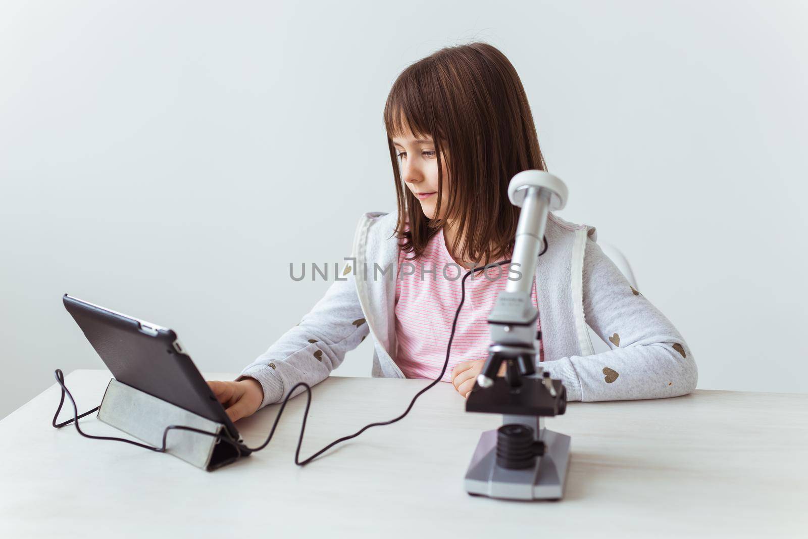 Portrait of cute little child doing homework with a digital microscope Technologies, science and children.