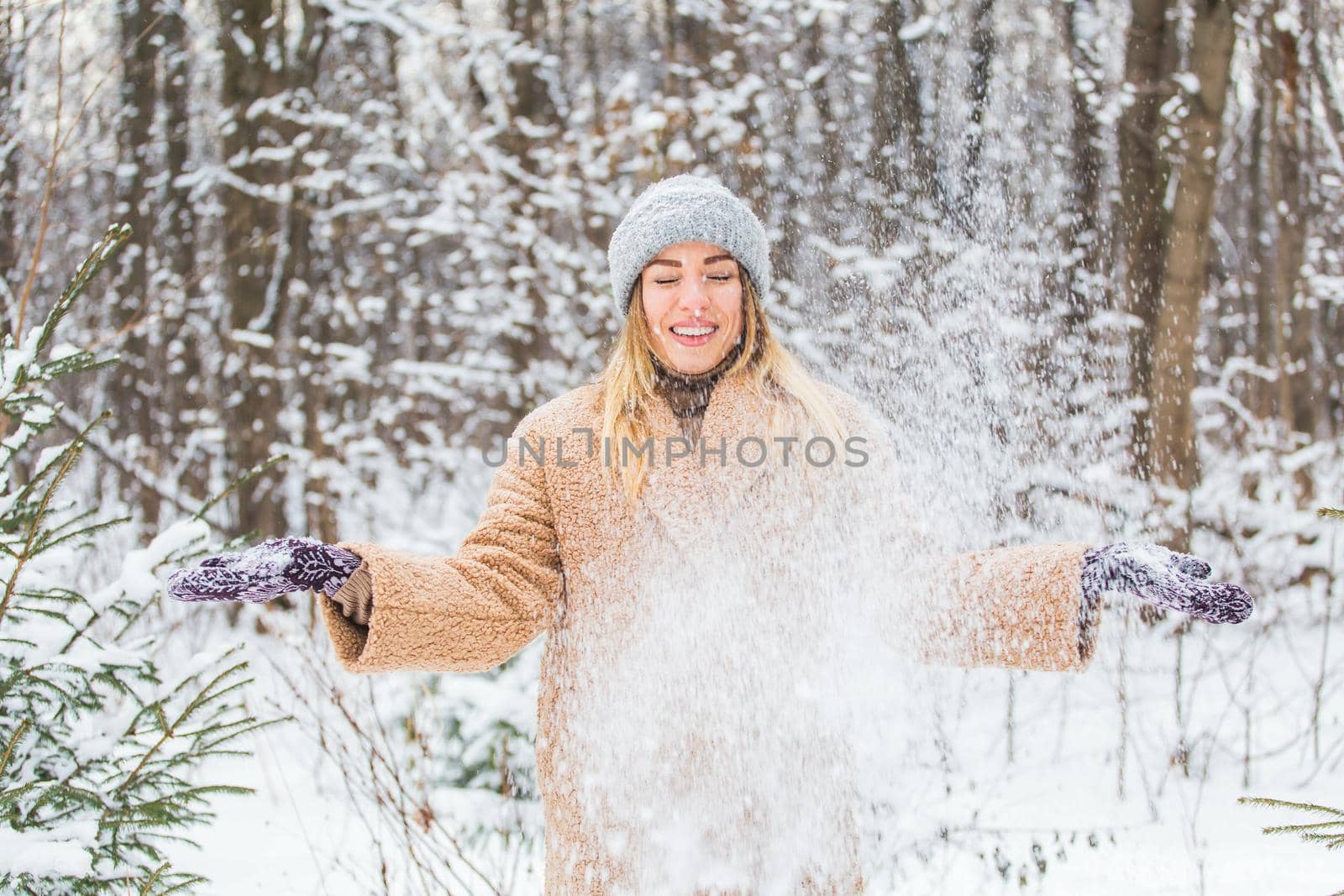 Young woman throwing snow in the air at sunny winter day, she is happy and fun. by Satura86