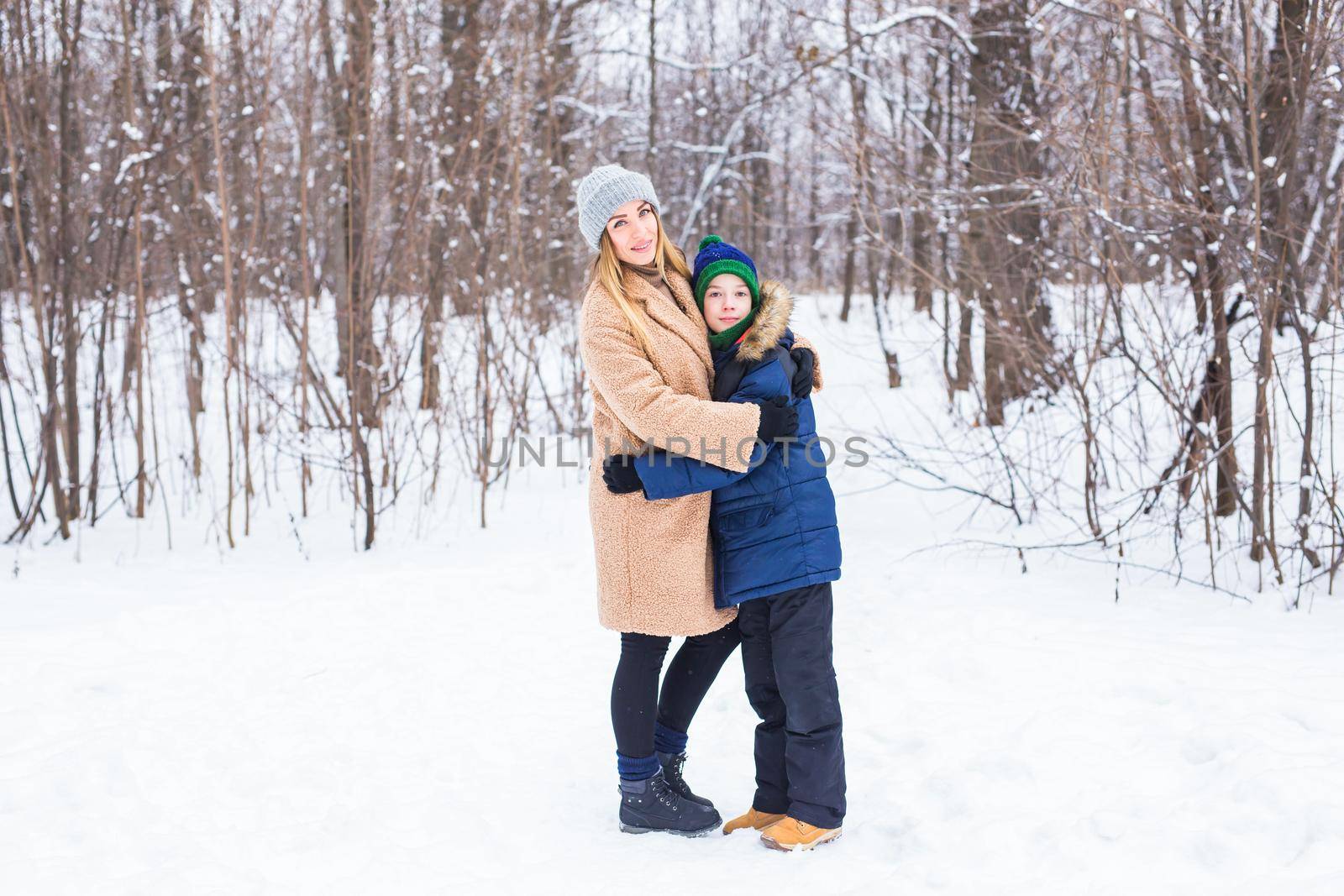 Portrait of happy mother with child son in winter outdoors. Snowy park. Single parent. by Satura86