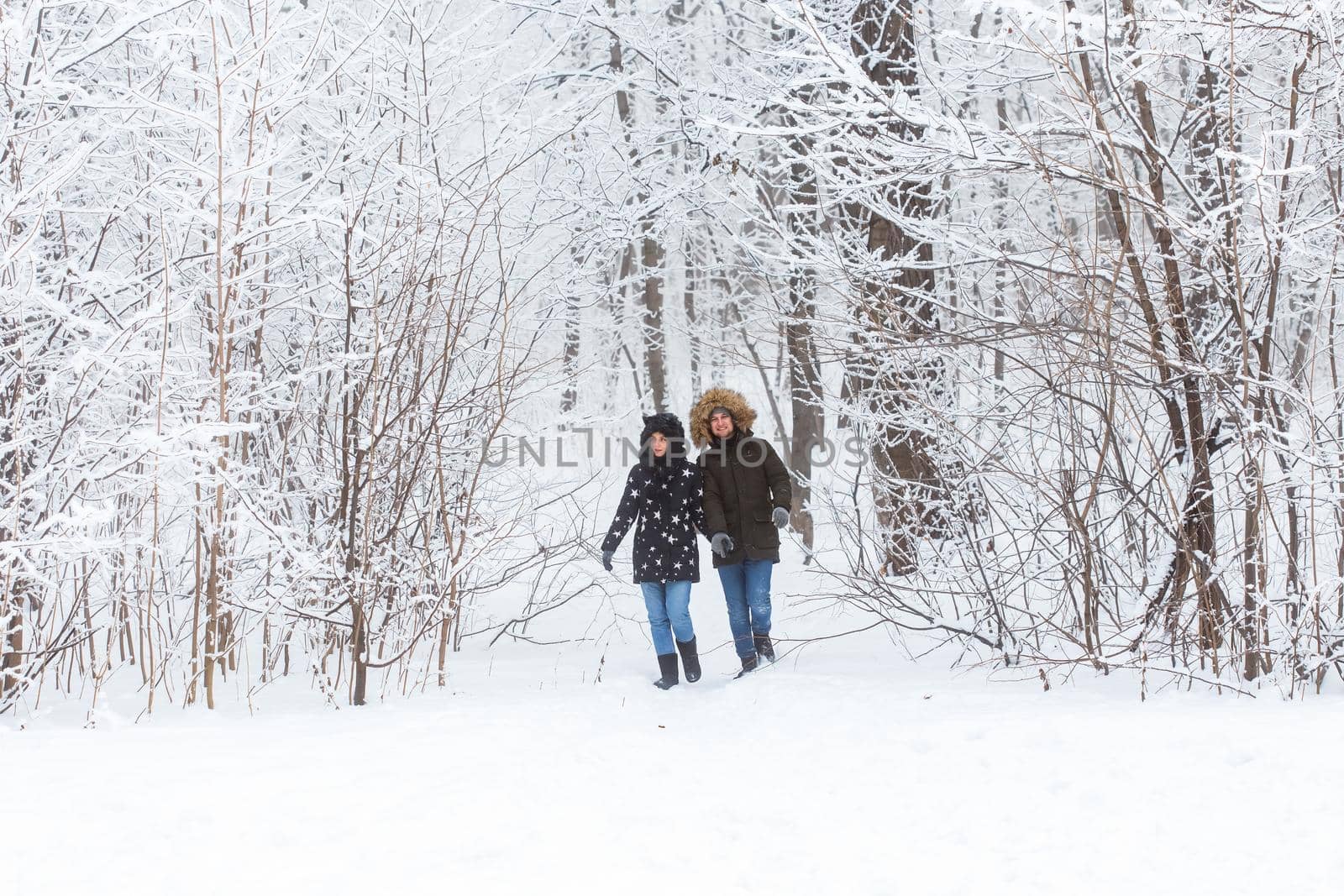 Young couple walking in a snowy park. Winter season