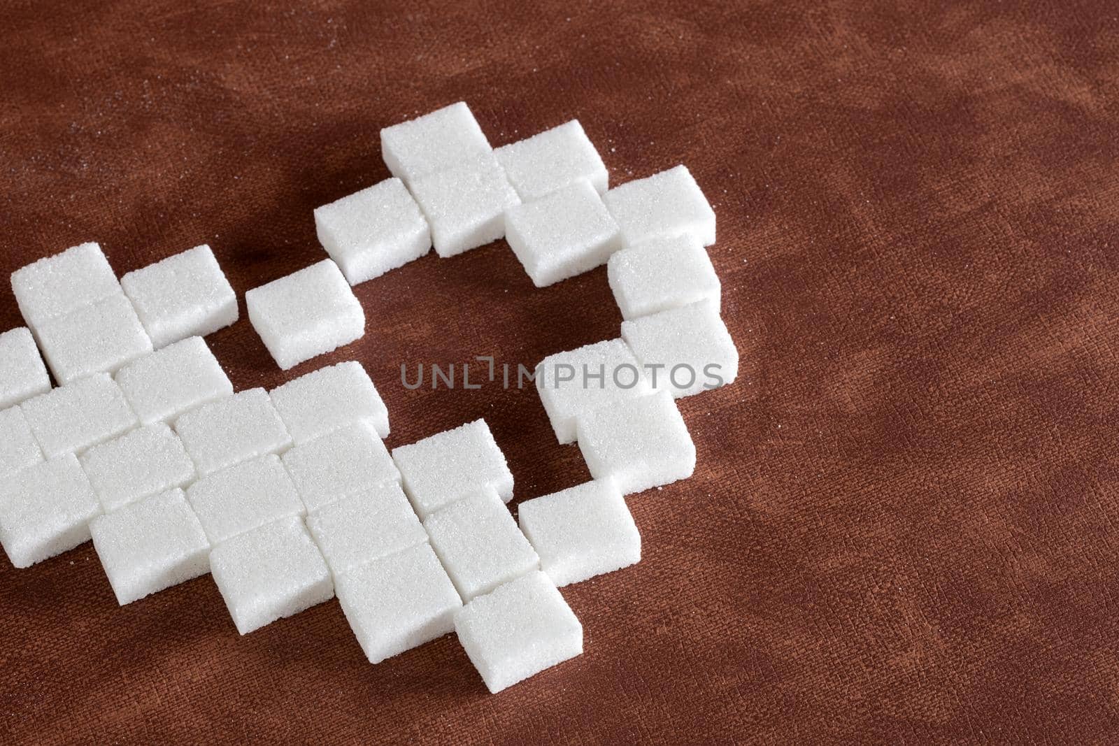 Sweet cute heart made of sugar cubes on brown natural background texture, love,sweets,candy,sugar,food concept modern design with hole