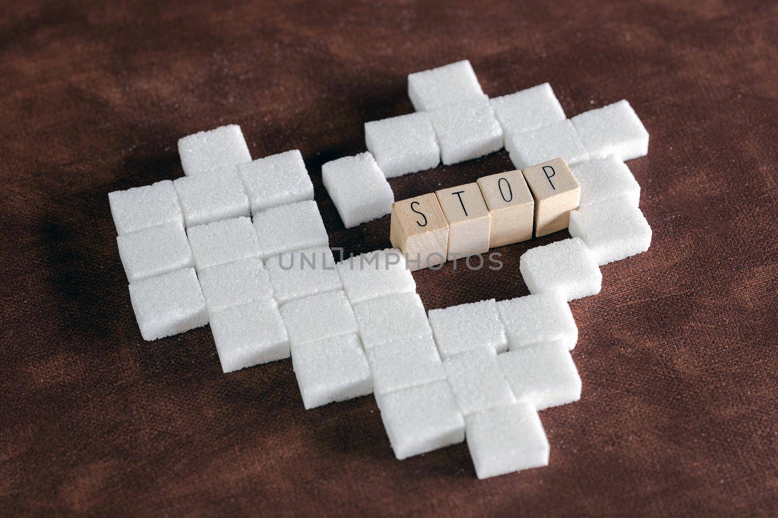 Sugar cubes in heart shape on brown background texture with Stop sign for diabetes. To stop diabetes, Health,sugar,junk food concept sweet modern design