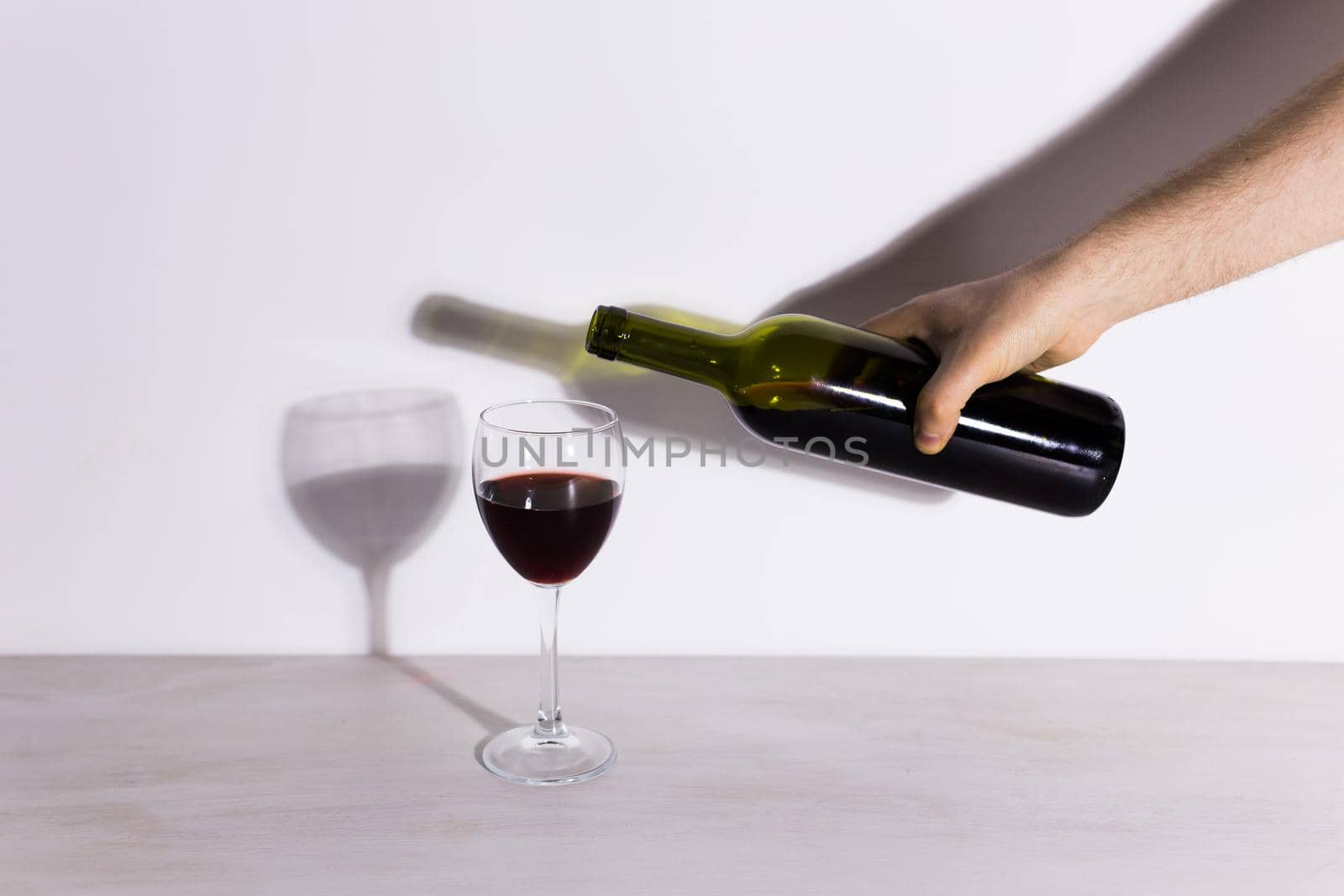 Pouring red wine into the glass against wooden background.