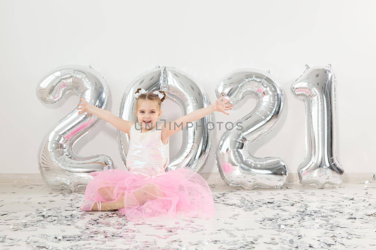 New year, holidays and celebration concept - Little girl sitting near with numbers balloons 2021