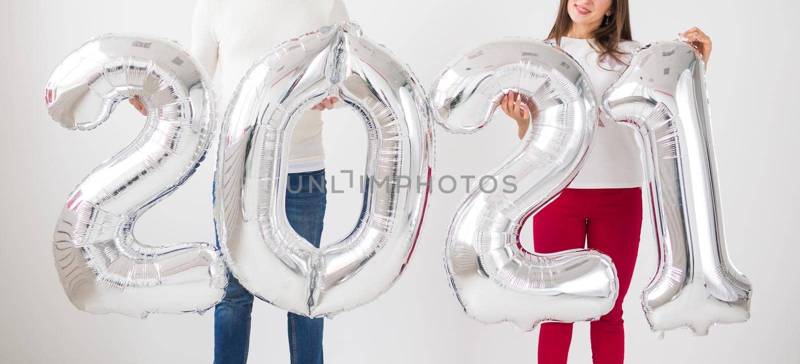 New 2021 Year is coming concept - Happy young man and woman are holding silver colored numbers indoors