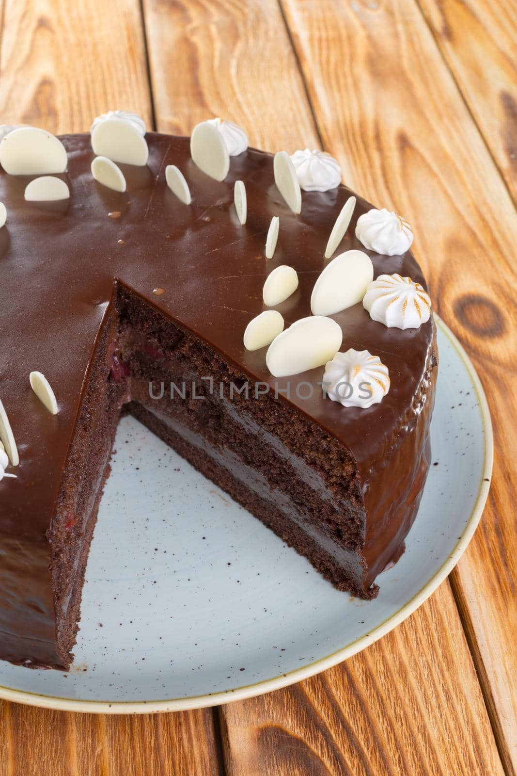 Cut chocolate cake on plate on wooden table close up
