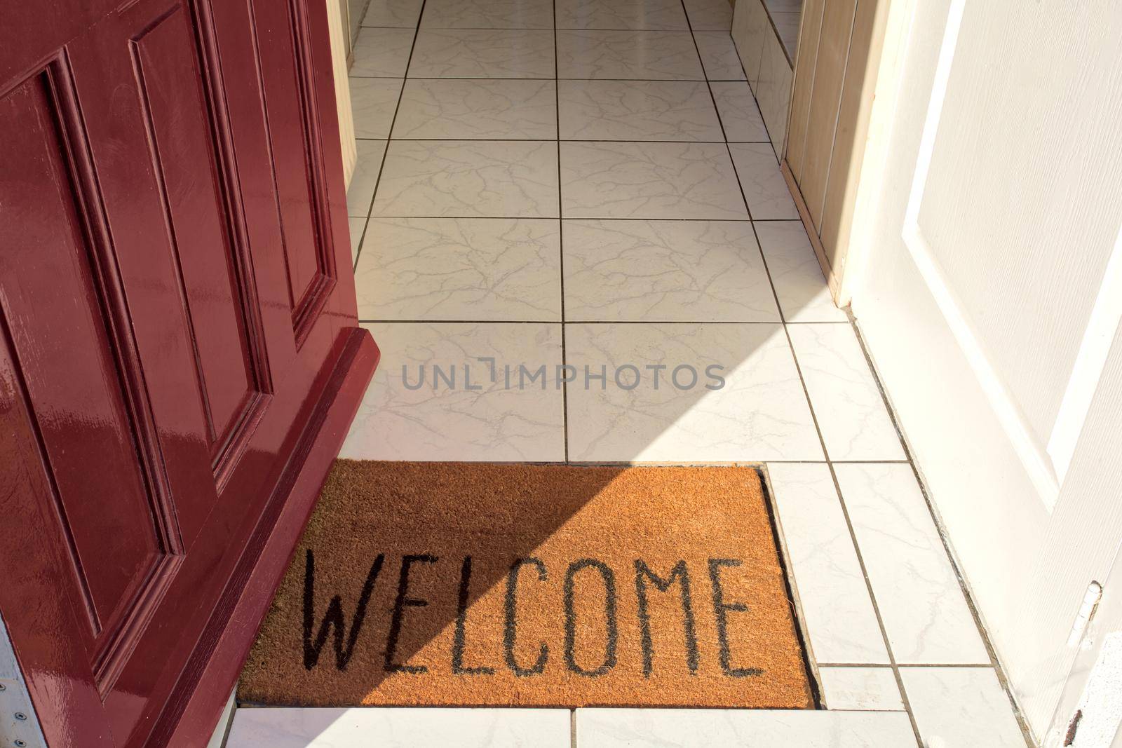 Open front door of house with Welcome door mat entering in the Hallway of a modern new home sunlight