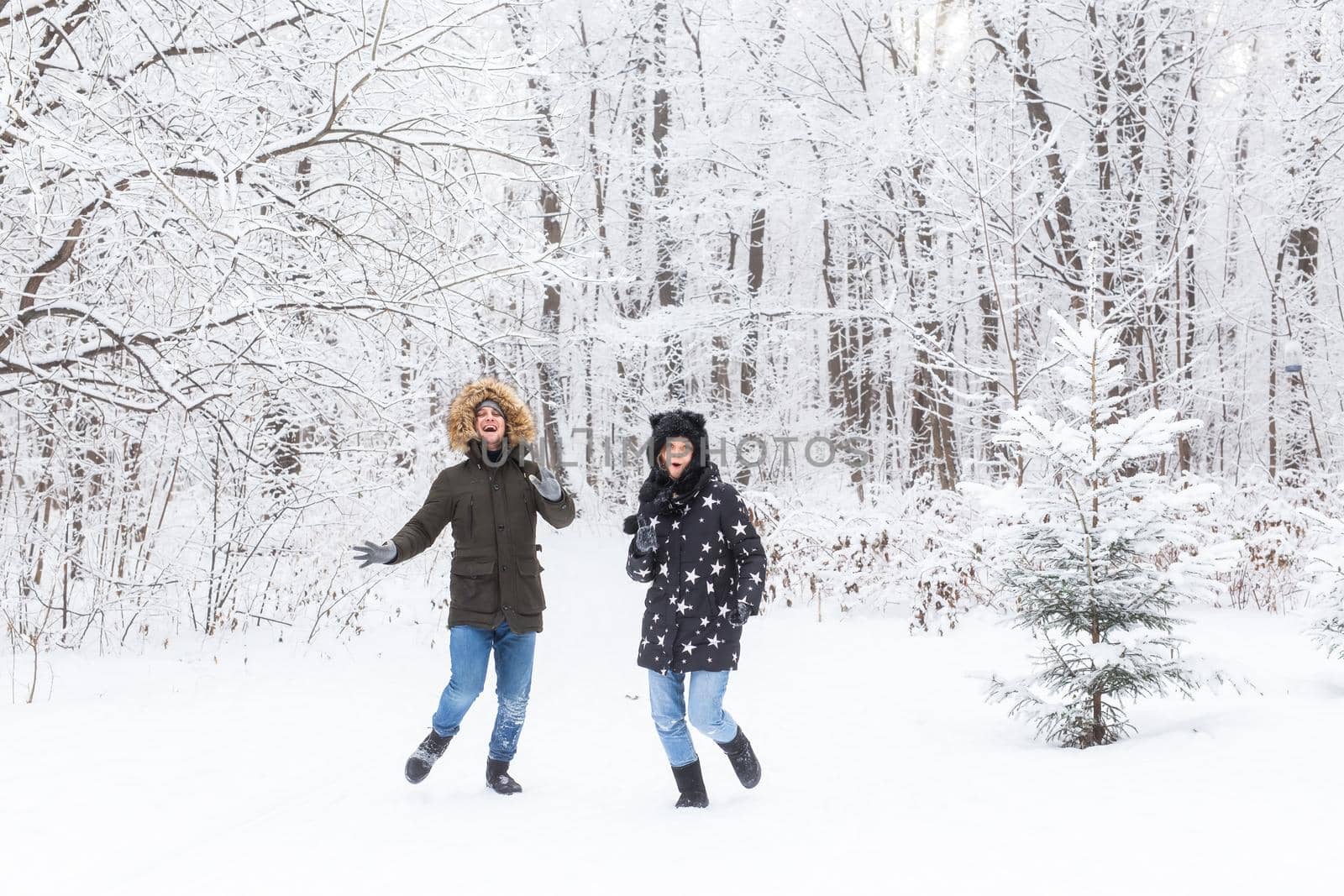 Fun, season and leisure concept - love couple plays winter wood on snow by Satura86
