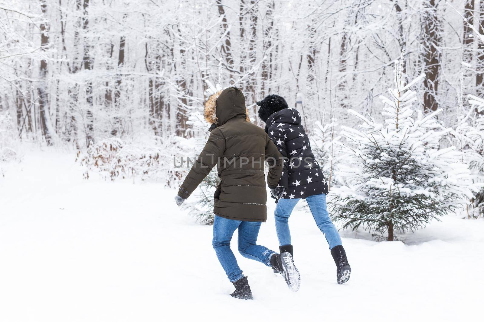 A young and beautiful couple is having fun in the park, running and holding hands. Valentine's Day and love story concept. Winter season.