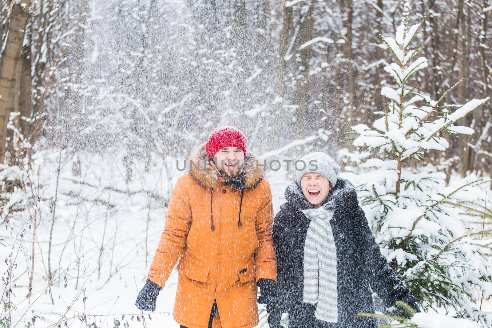 Love, season, friendship and people concept - happy young man and woman having fun and playing with snow in winter forest by Satura86