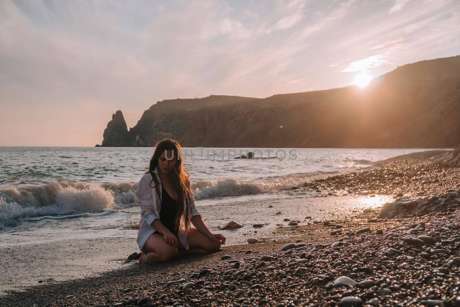 Selective focus. Happy carefree sensual woman with long hair in black swimwear posing at sunset beach. Silhouette of young beautiful playful positive woman outdoor. Summer vacation and trip concept by panophotograph