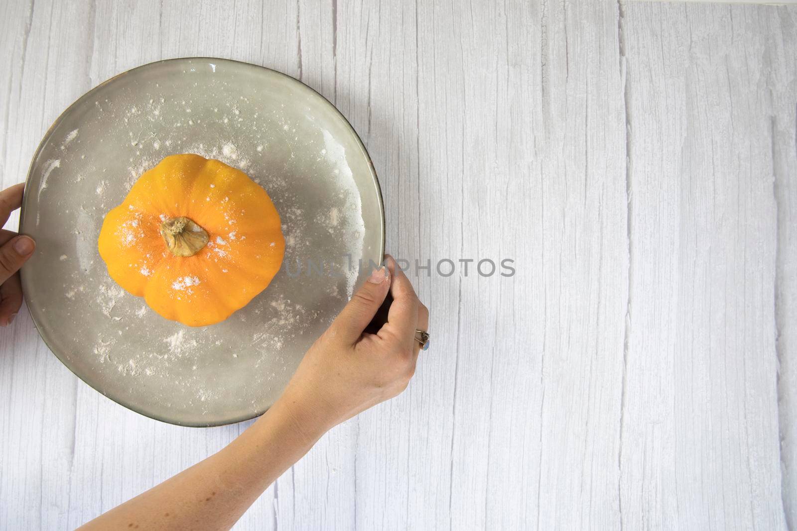 Orange pumpkin on white wooden background with copy space on natural plate top view, autumn harvest, Halloween or Thanksgiving concept space for text