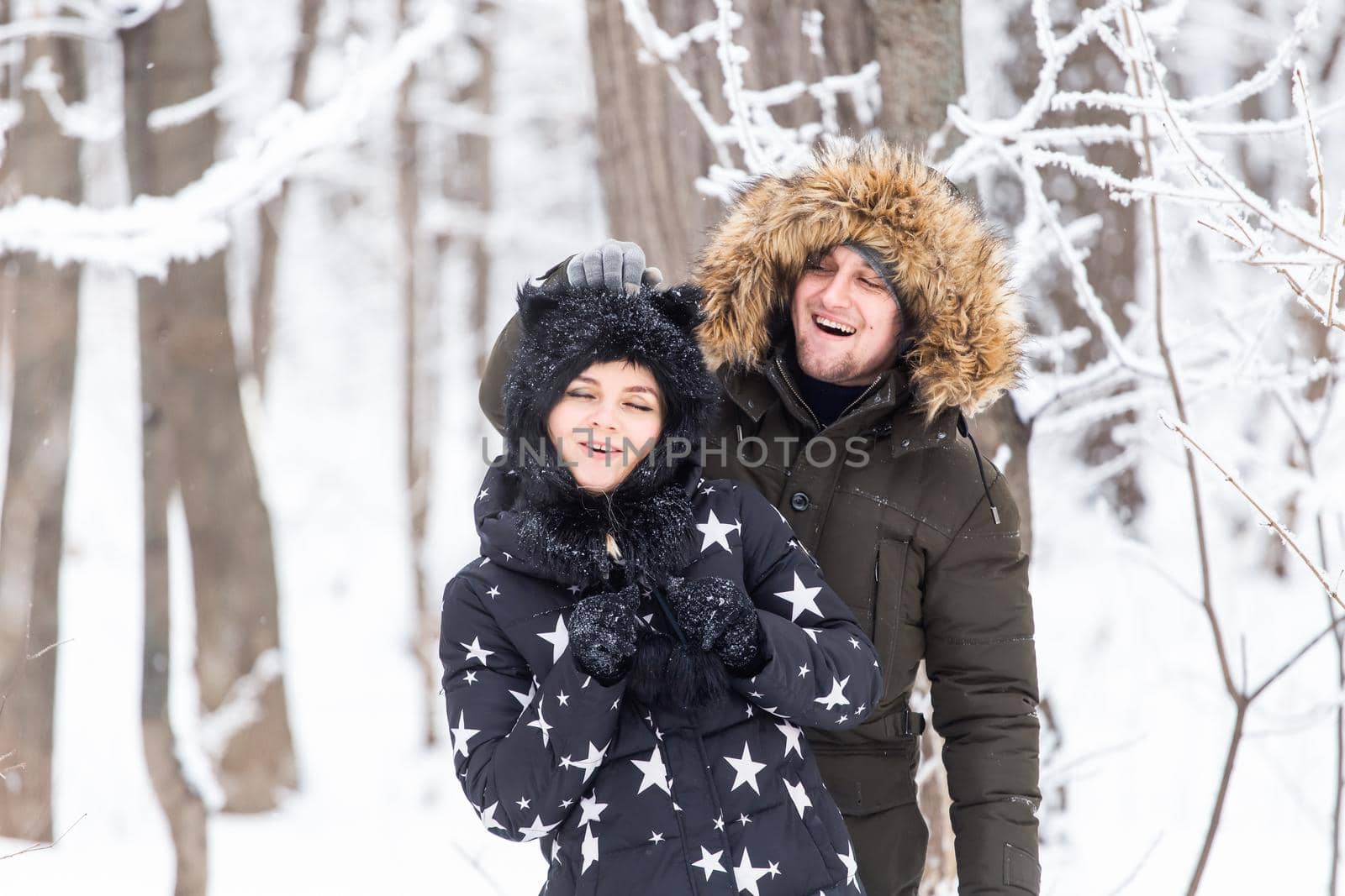 Fun, season and leisure concept - love couple plays winter wood on snow.