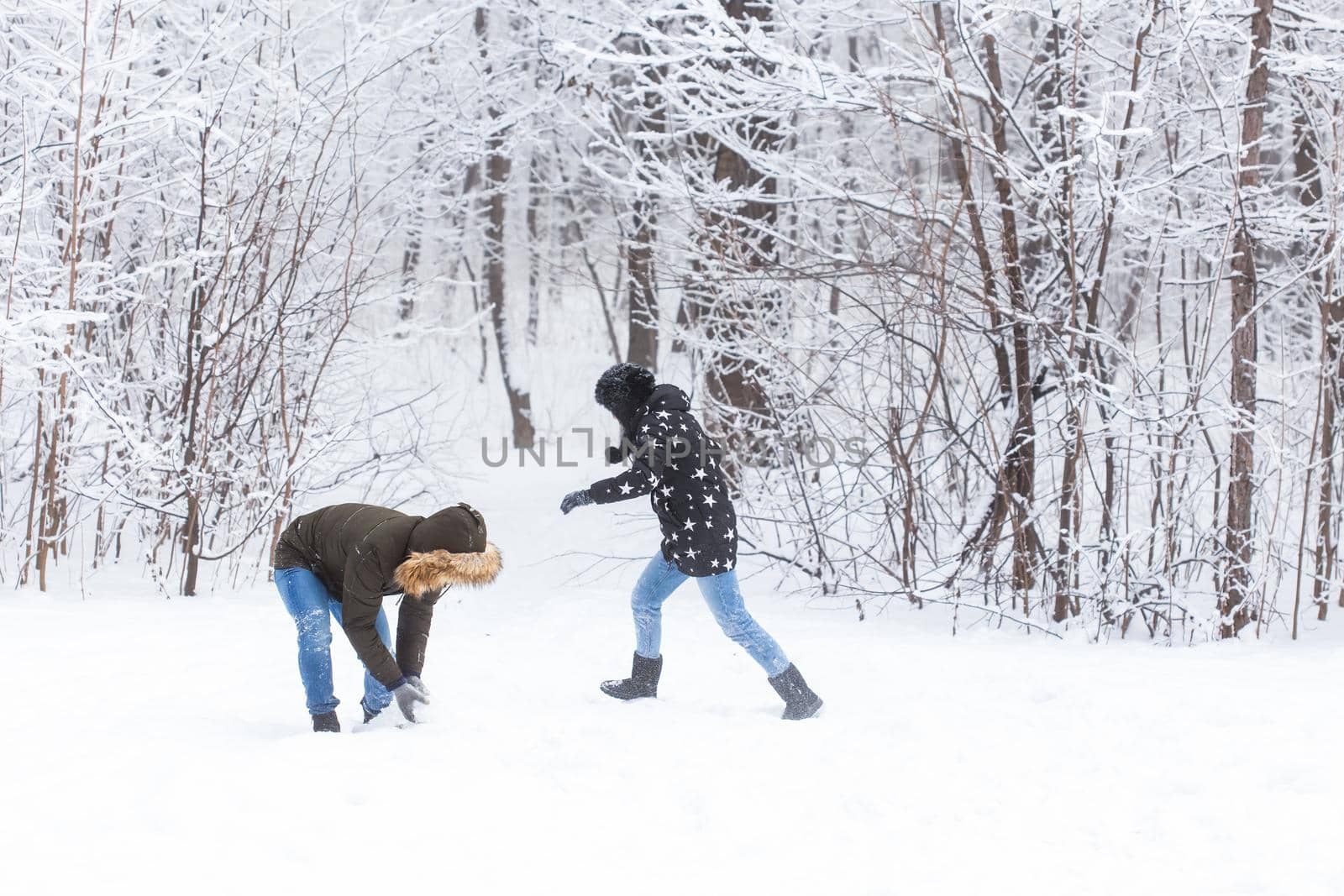 Fun, season and leisure concept - love couple plays winter wood on snow by Satura86