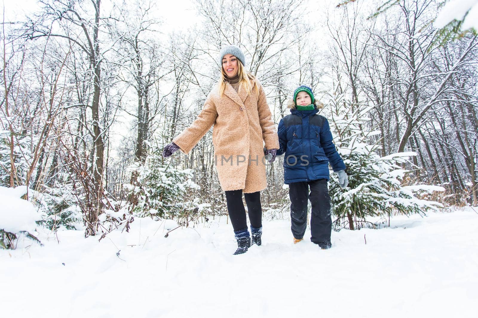 Parenting, fun and season concept - Happy mother and son having fun and playing with snow in winter forest by Satura86