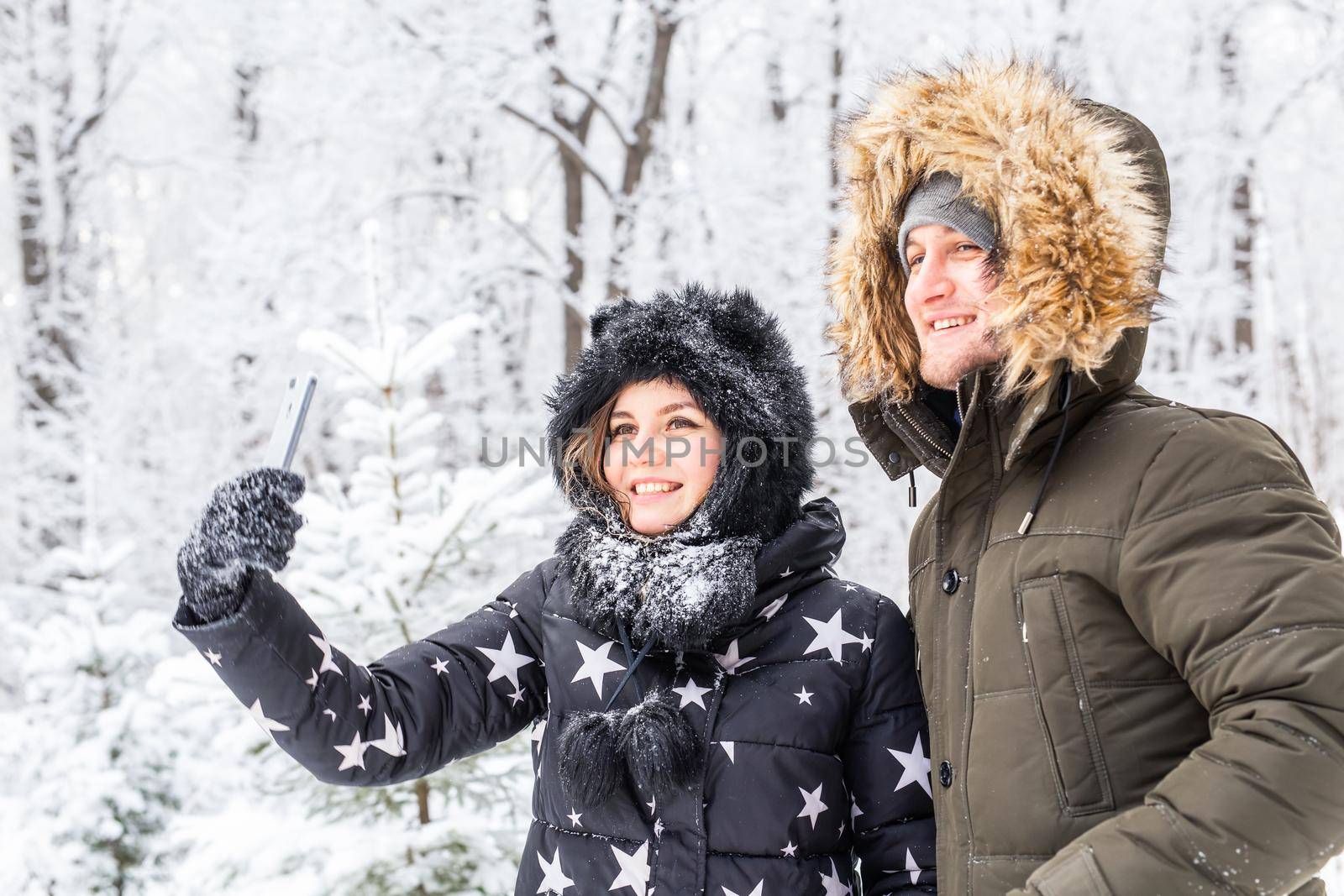 Season, love, technology and leisure concept - happy couple taking selfie by smartphone over winter background by Satura86