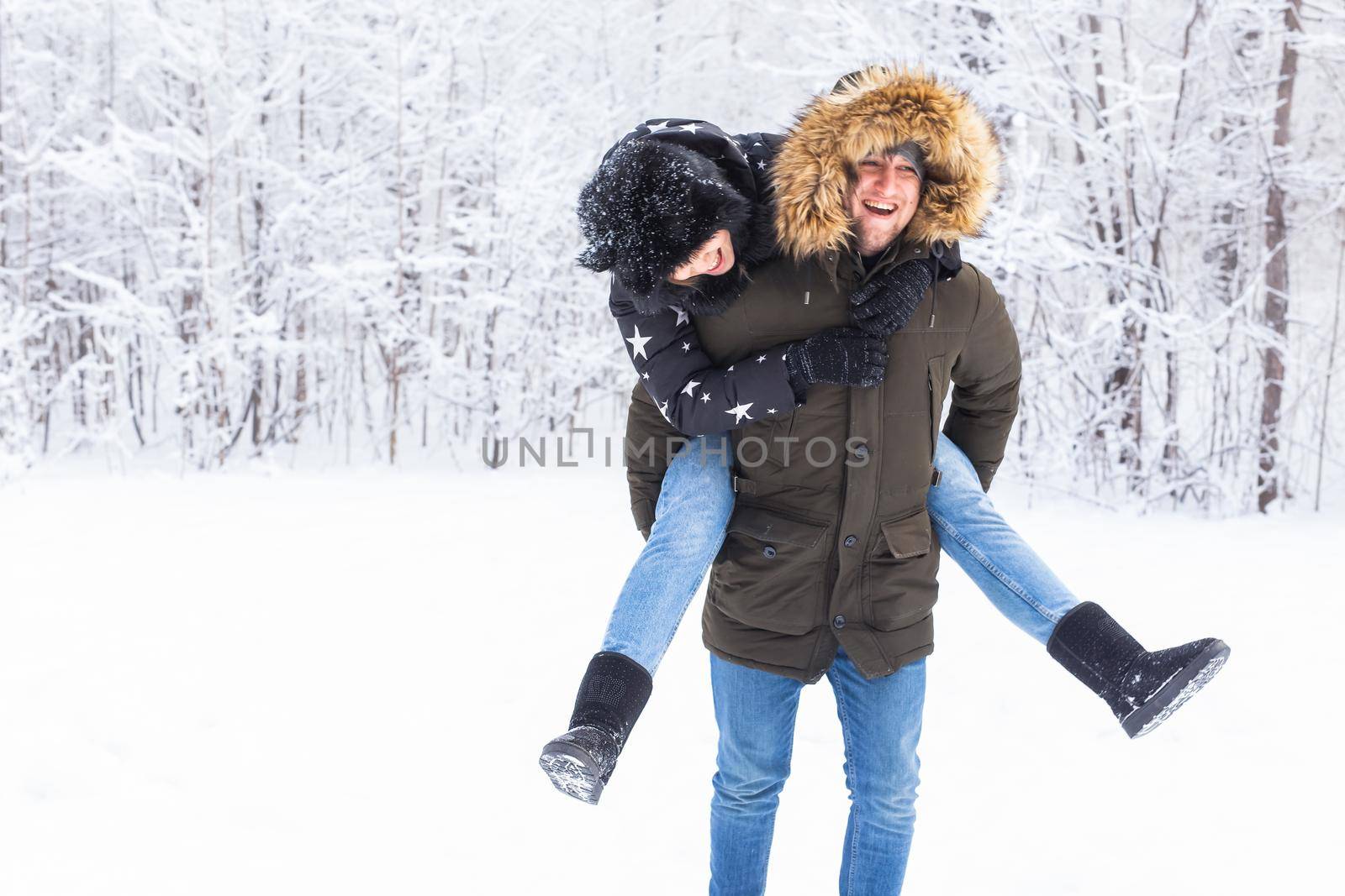 Portrait of happy young couple in winter park with their friend behind.