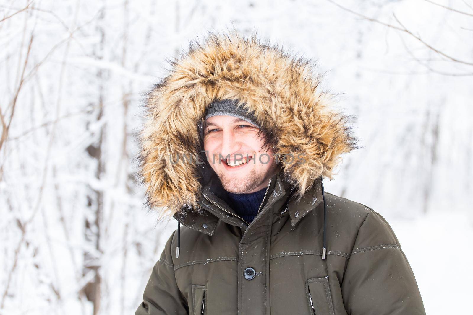 Handsome man in winter hat smiling portrait on snowy nature.