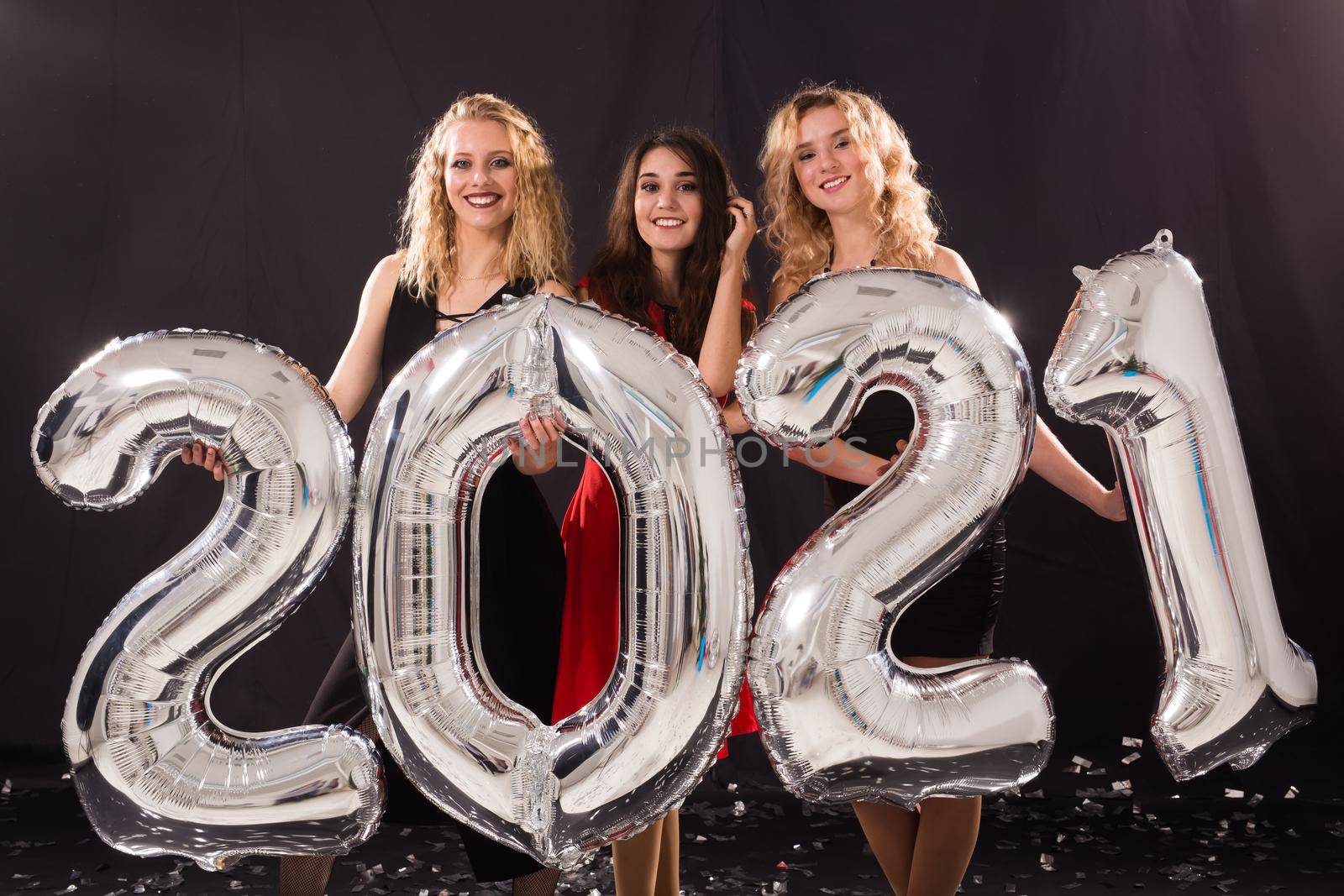 Party and new year holidays concept - cheerful young women celebrating new years eve 2021