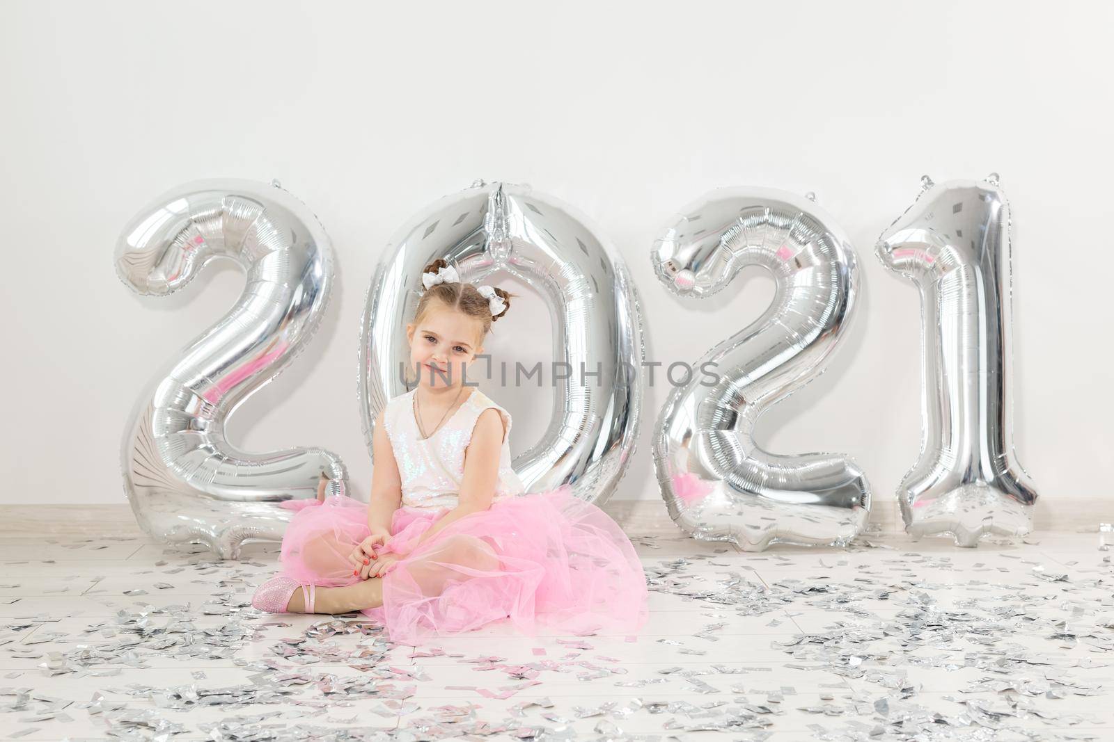 New year, holidays and celebration concept - Little girl sitting near with numbers balloons 2021