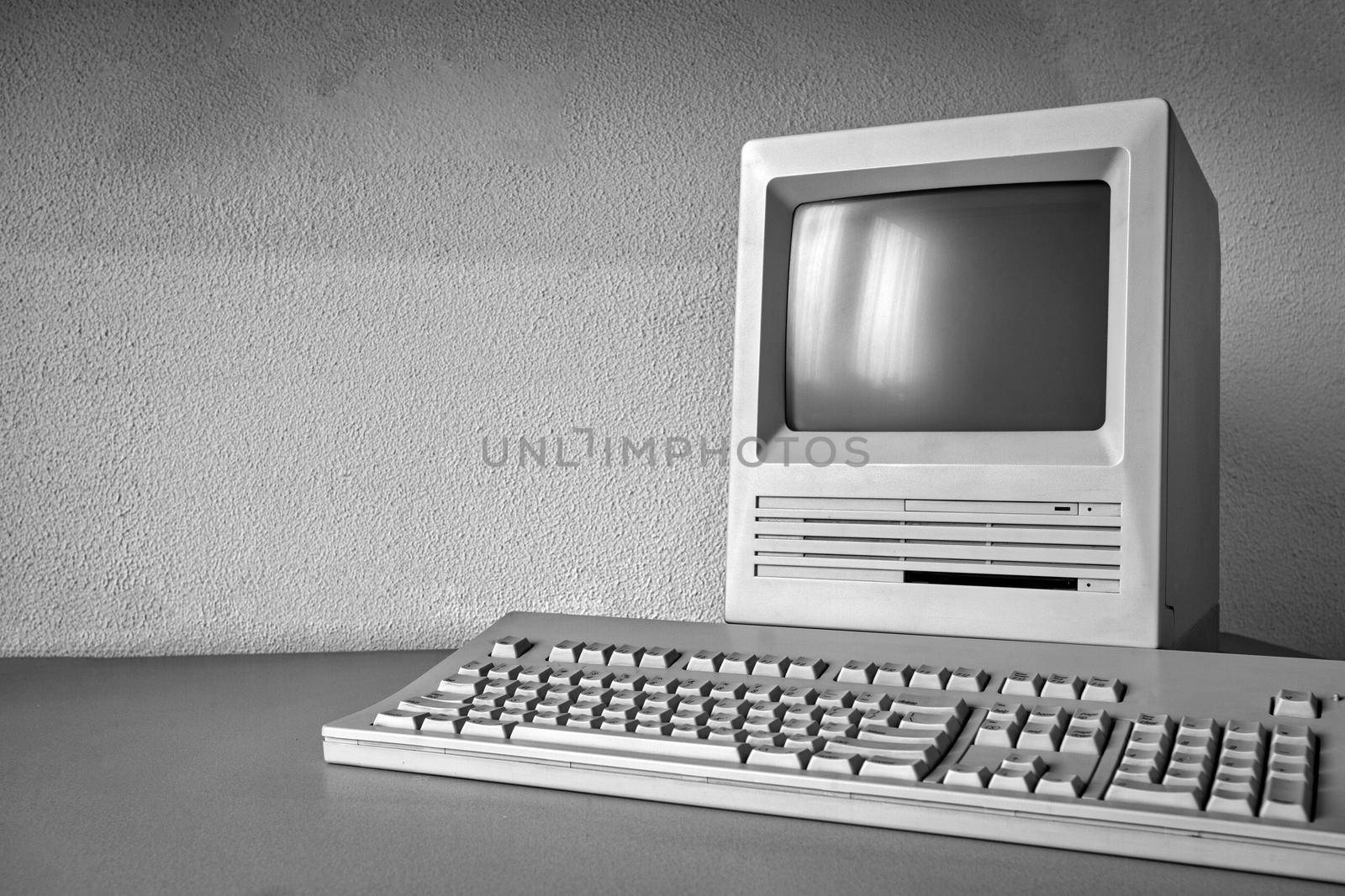 Old vintage monitor and computer on desk, retro workplace with copy space business, technology,internet concept near white wall