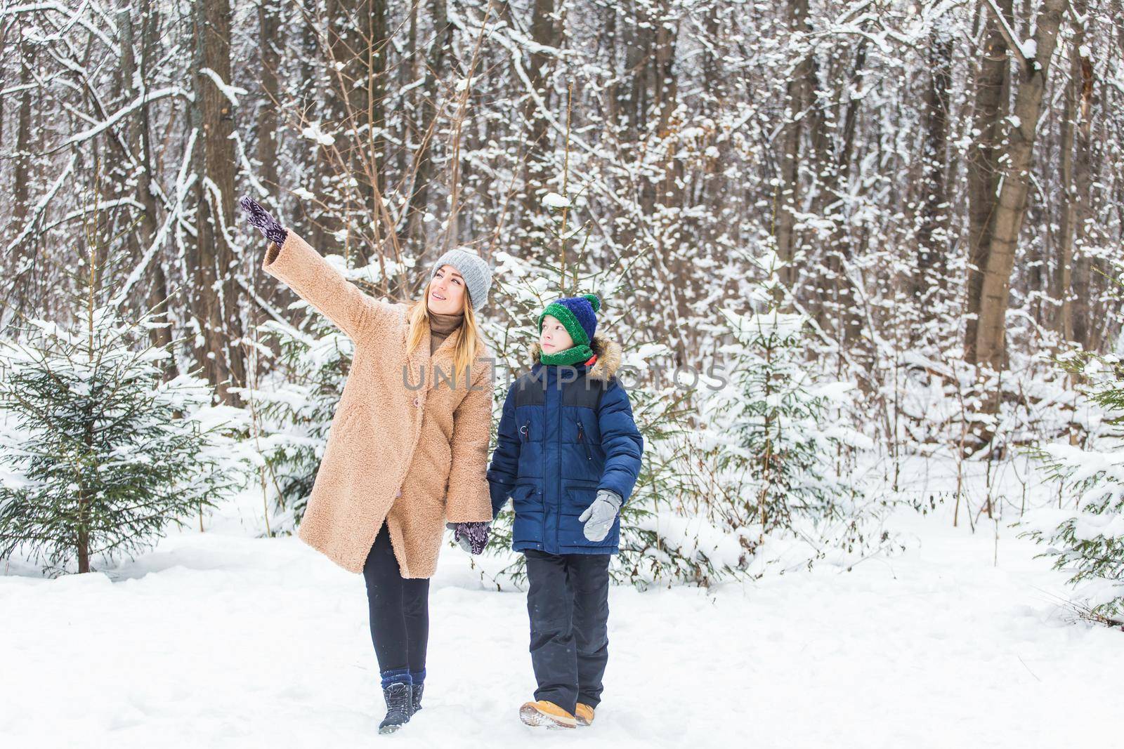 Portrait of happy mother with child son in winter outdoors. Snowy park. Single parent. by Satura86