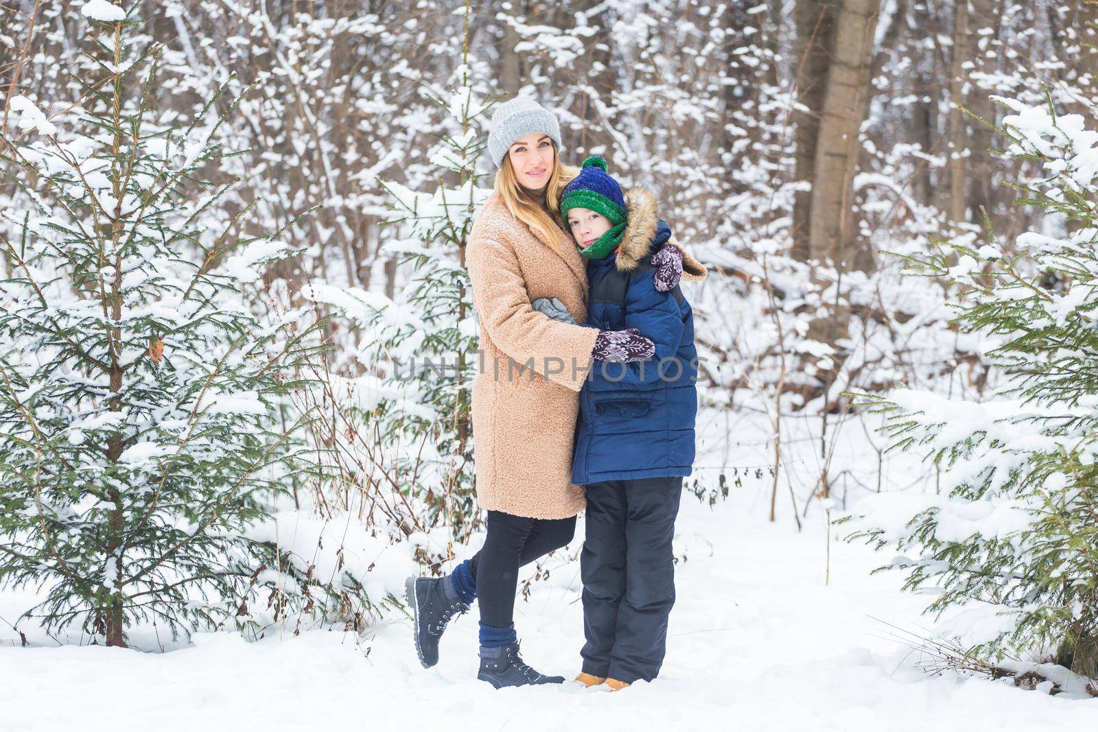 Portrait of happy mother with child son in winter outdoors. Snowy park. Single parent. by Satura86