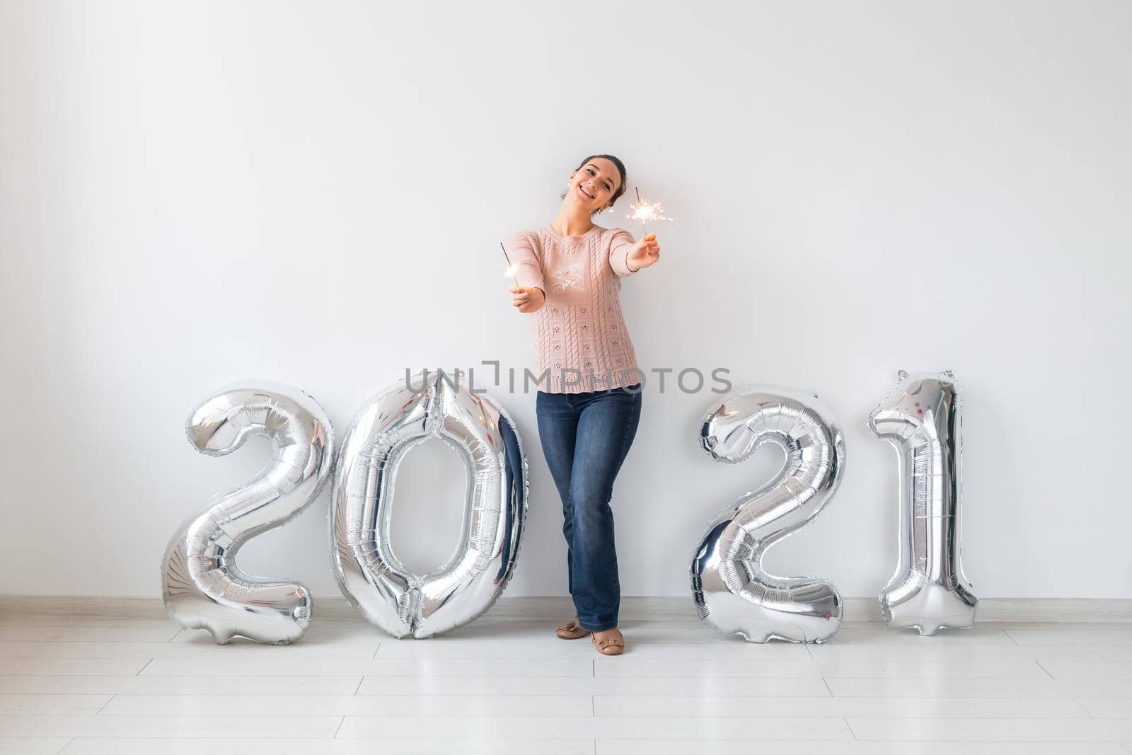 New Year celebration and party concept - Happy young woman with sparklers near silver 2021 balloons on white background