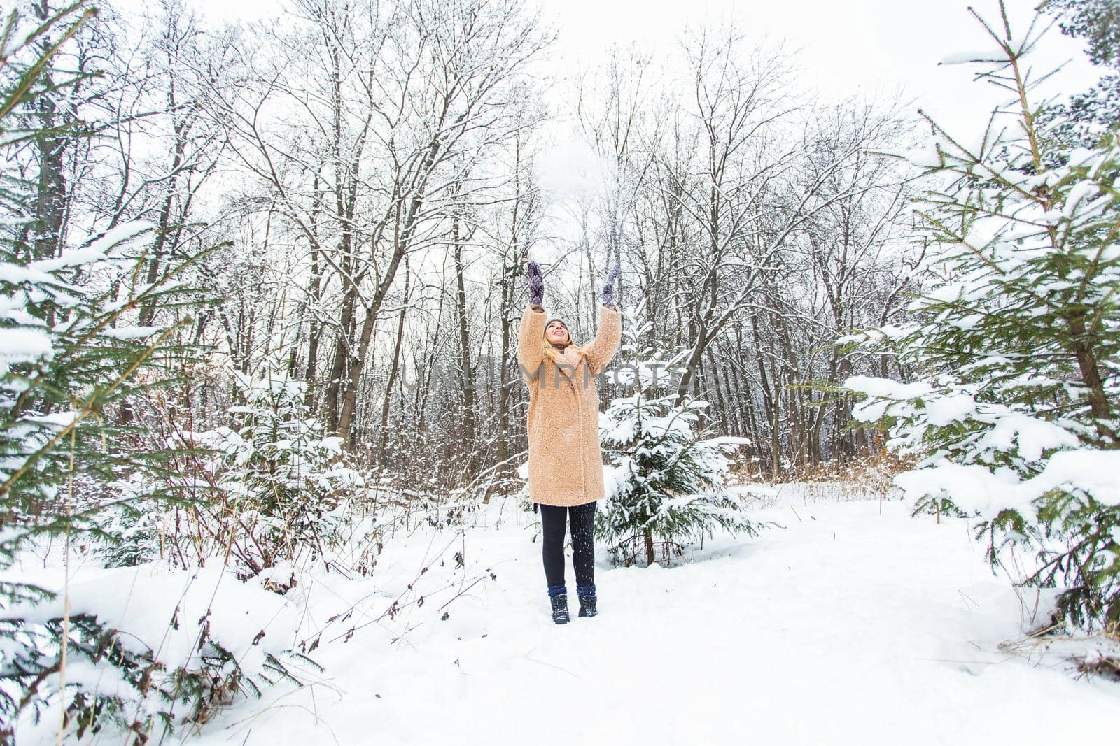 Young woman throwing snow in the air at sunny winter day, she is happy and fun. by Satura86