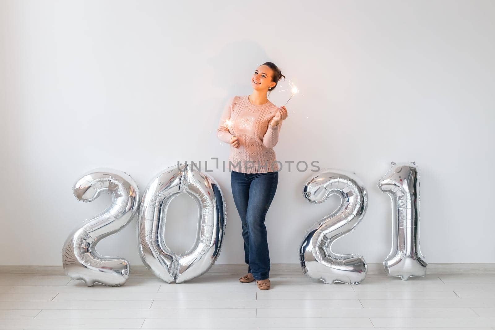 New Year celebration and party concept - Happy young woman with sparklers near silver 2021 balloons on white background