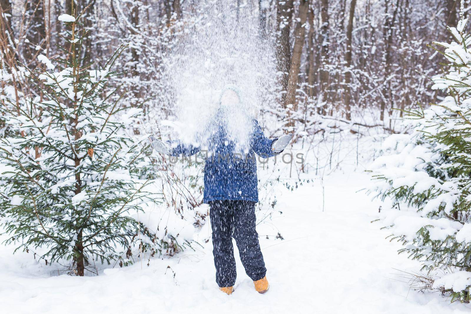 Young boy plays with snow, have fun, smiles. Teenager in winter park. Active lifestyle, winter activity, outdoor winter games, snowballs.