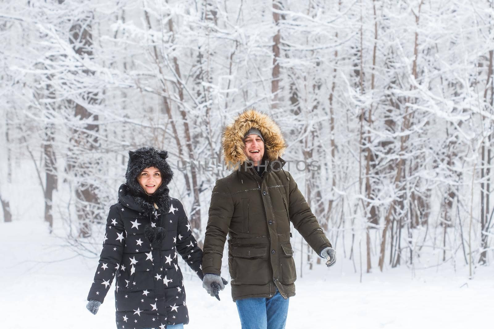 Young couple in love walks in the snowy forest. Active winter holidays
