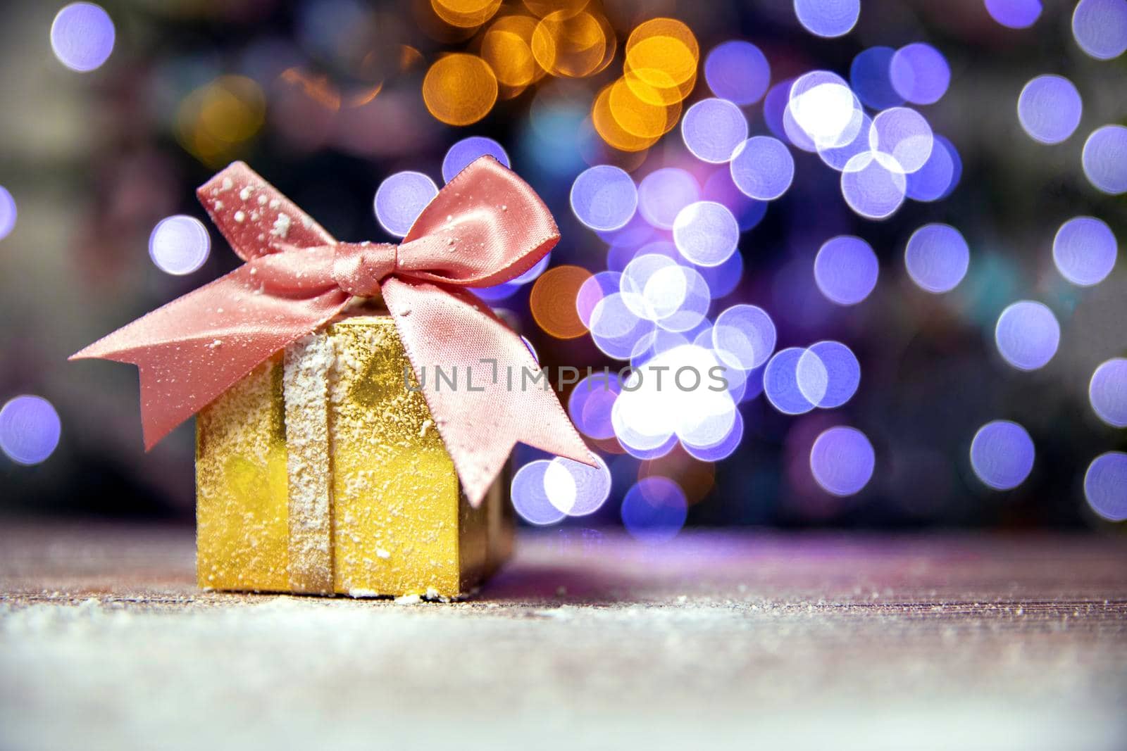 Merry Christmas, New Year, gifts in gold boxes with pink bow in the snow, bokeh Christmas tree background with copy space, Holiday,present concept space for text