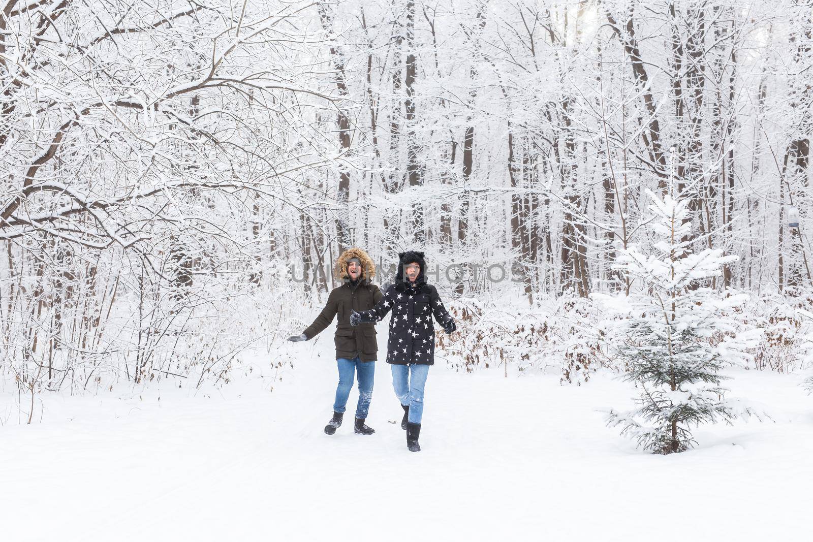 A young and beautiful couple is having fun in the park, running and holding hands. Valentine's Day and love story concept. Winter season.