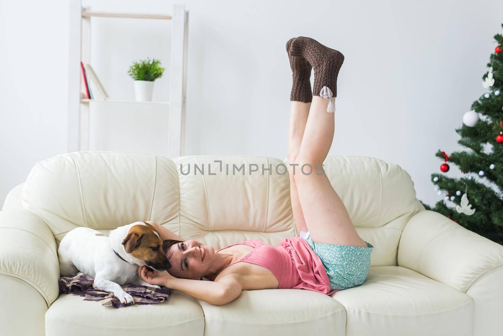 Happy young woman with lovely dog in living room with christmas tree. Holidays concept. by Satura86