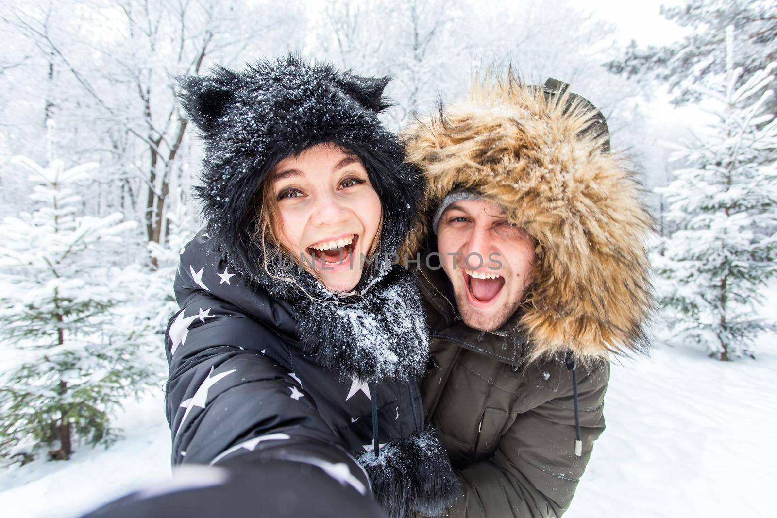 Season, love, technology and leisure concept - happy couple taking selfie by smartphone over winter.