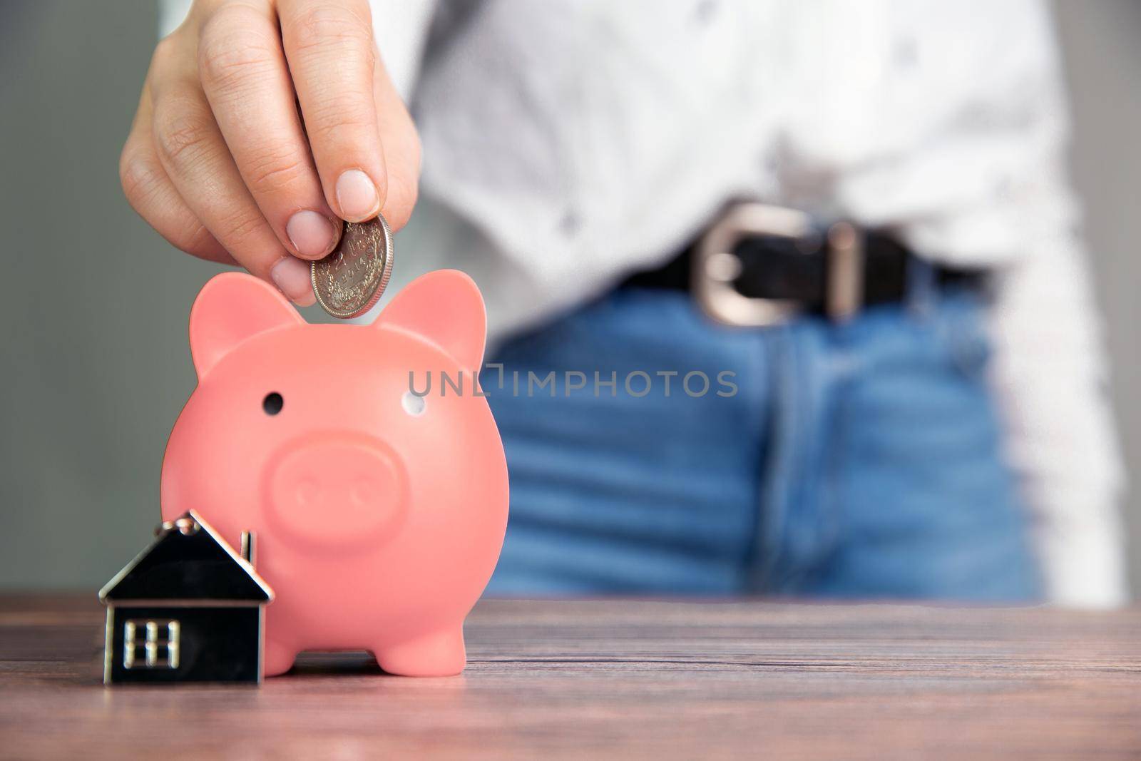 Money saving for buying a new house in pink piggy bank , real estate,mortgage,loans,business concept with space for text copy space on wooden table