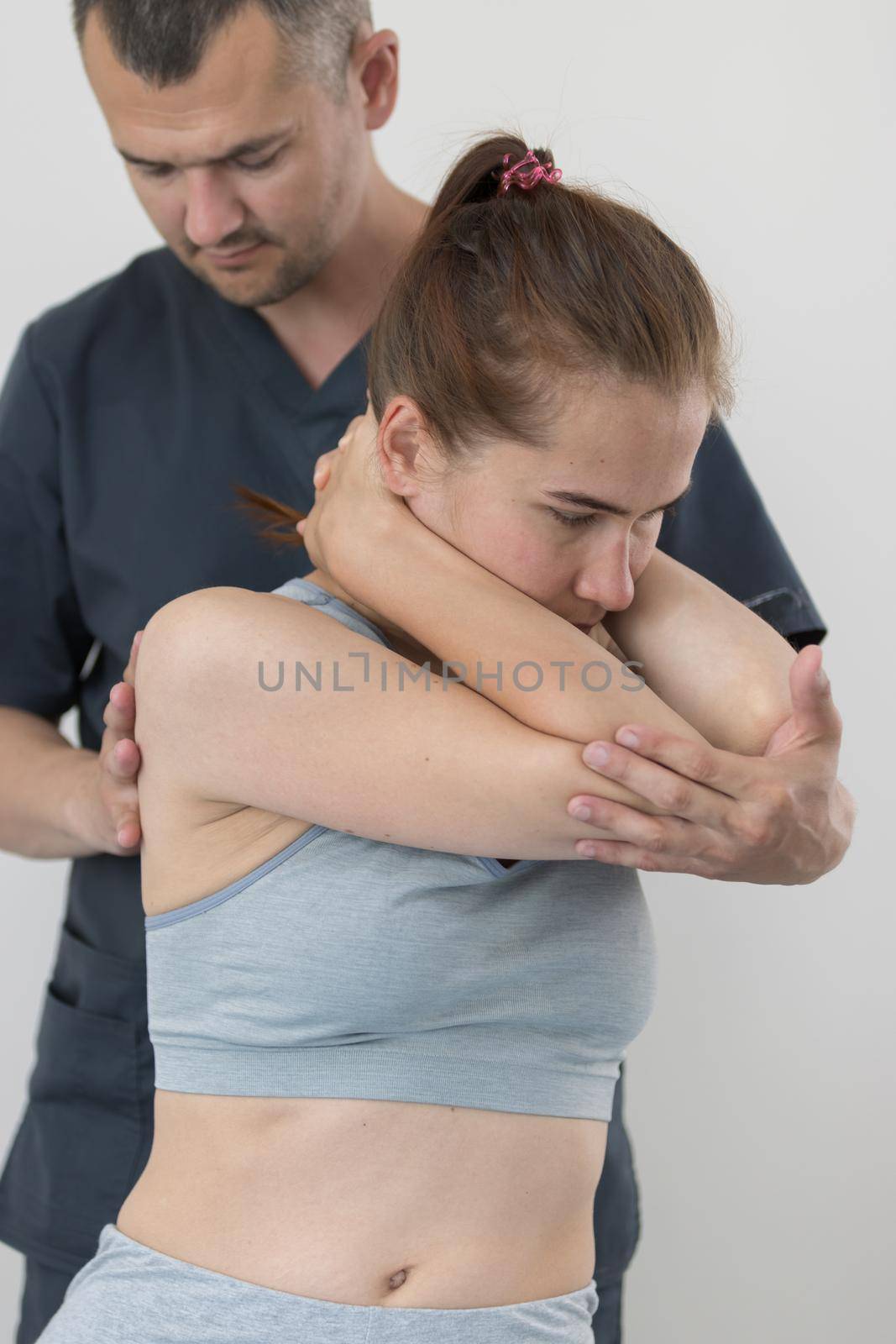 Chiropractic treatment - the doctor knocks the young woman's elbows together and turning her to the side. Mid shot