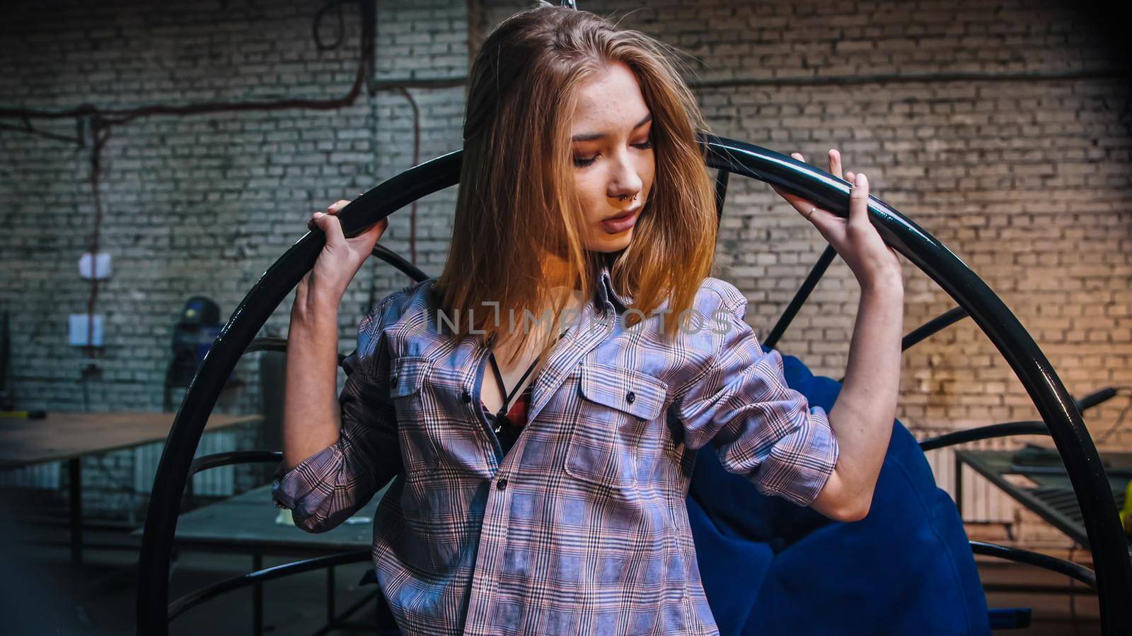 Young attractive woman in open shirt standing in workshop. Portrait