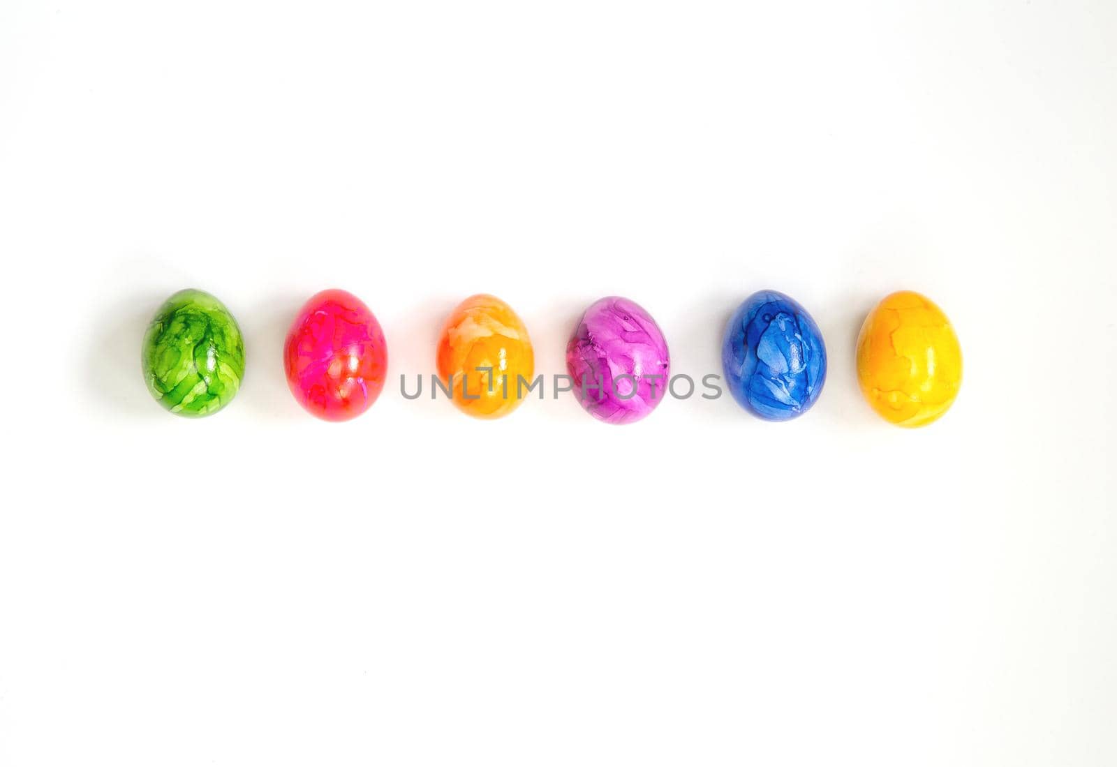 Row of Colorful painted Easter Eggs isolated on white background surrounded with flowers top view background, Happy Easter concept modern design copy space