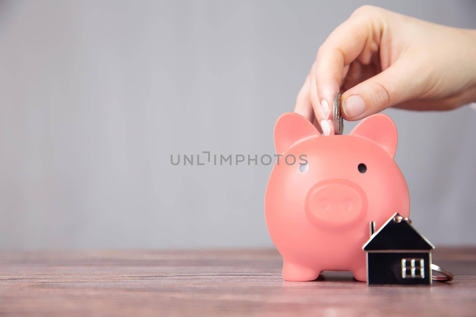 Money saving for buying a new house in pink piggy bank , real estate,mortgage,loans,business concept with space for text copy space on wooden table