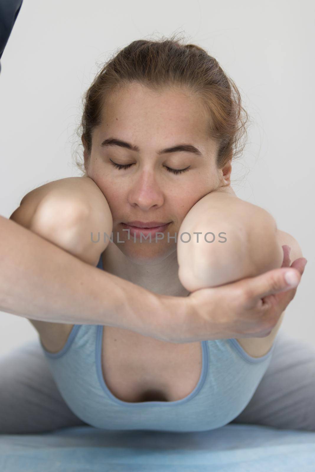 Young woman having osteopathy treatment - lying in the pose with her elbows forward. Mid shot