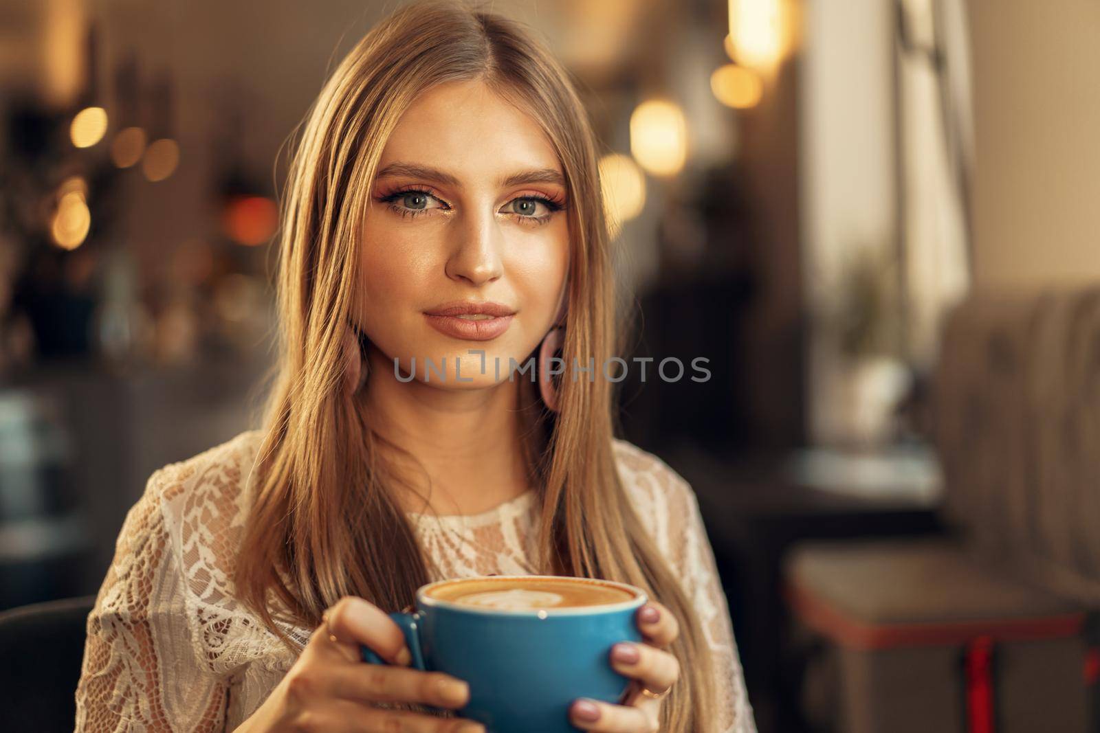 Beautiful young woman sitting in coffee shop enjoying her drink. High quality photo