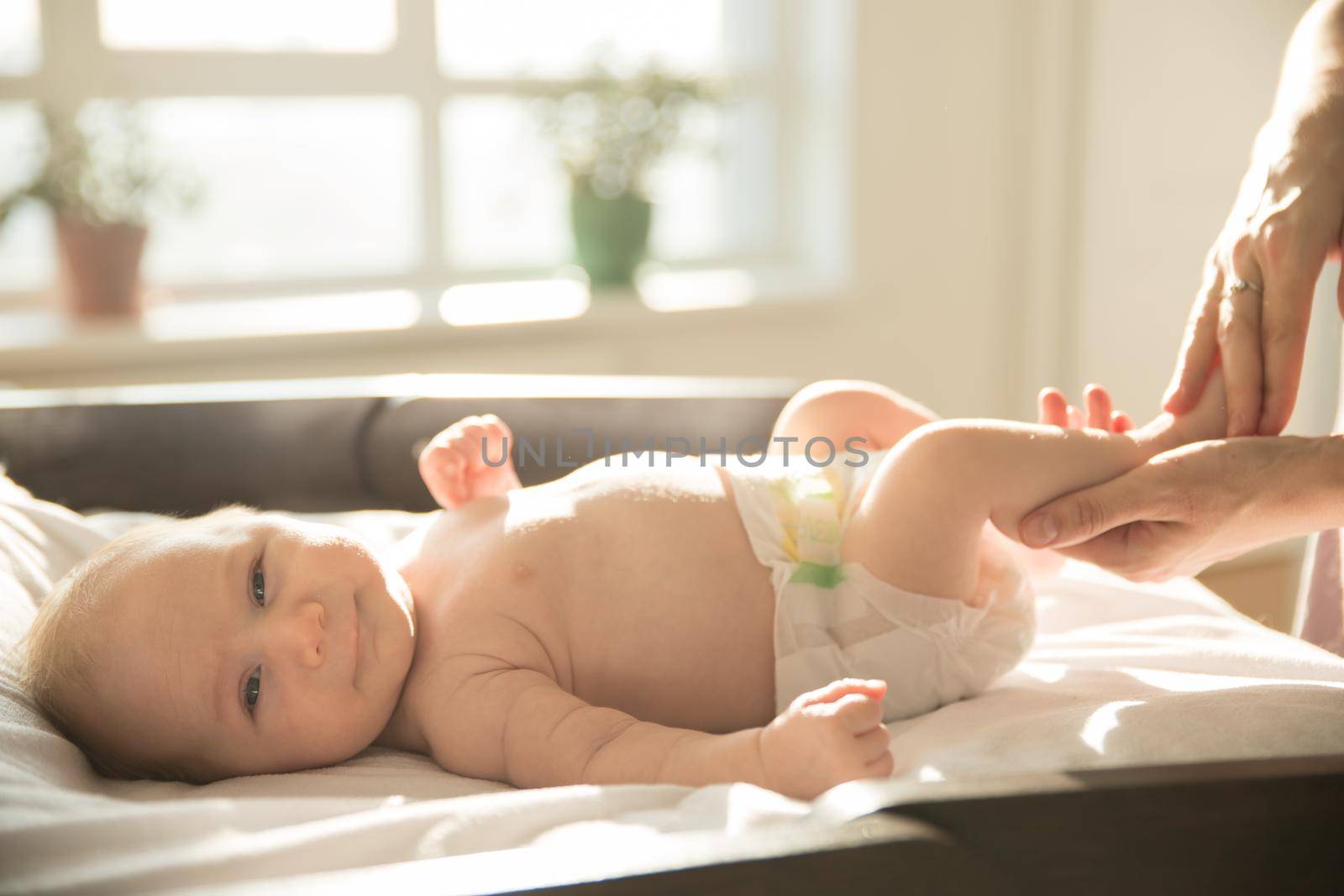 Parent massaging legs of her little baby. Mid shot