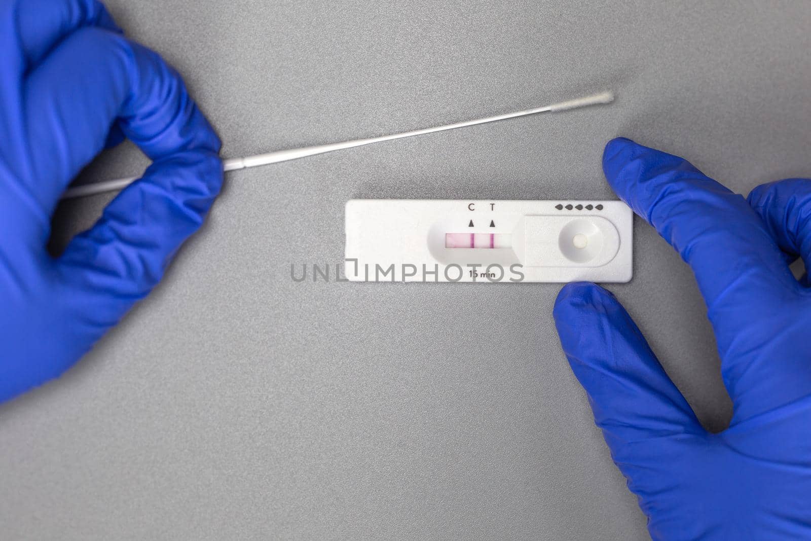 Self test kit for Covid-19 at home showing positive on gray background, Coronavirus,Covid,Health,Home test, concept with copy space and surgical gloves close up