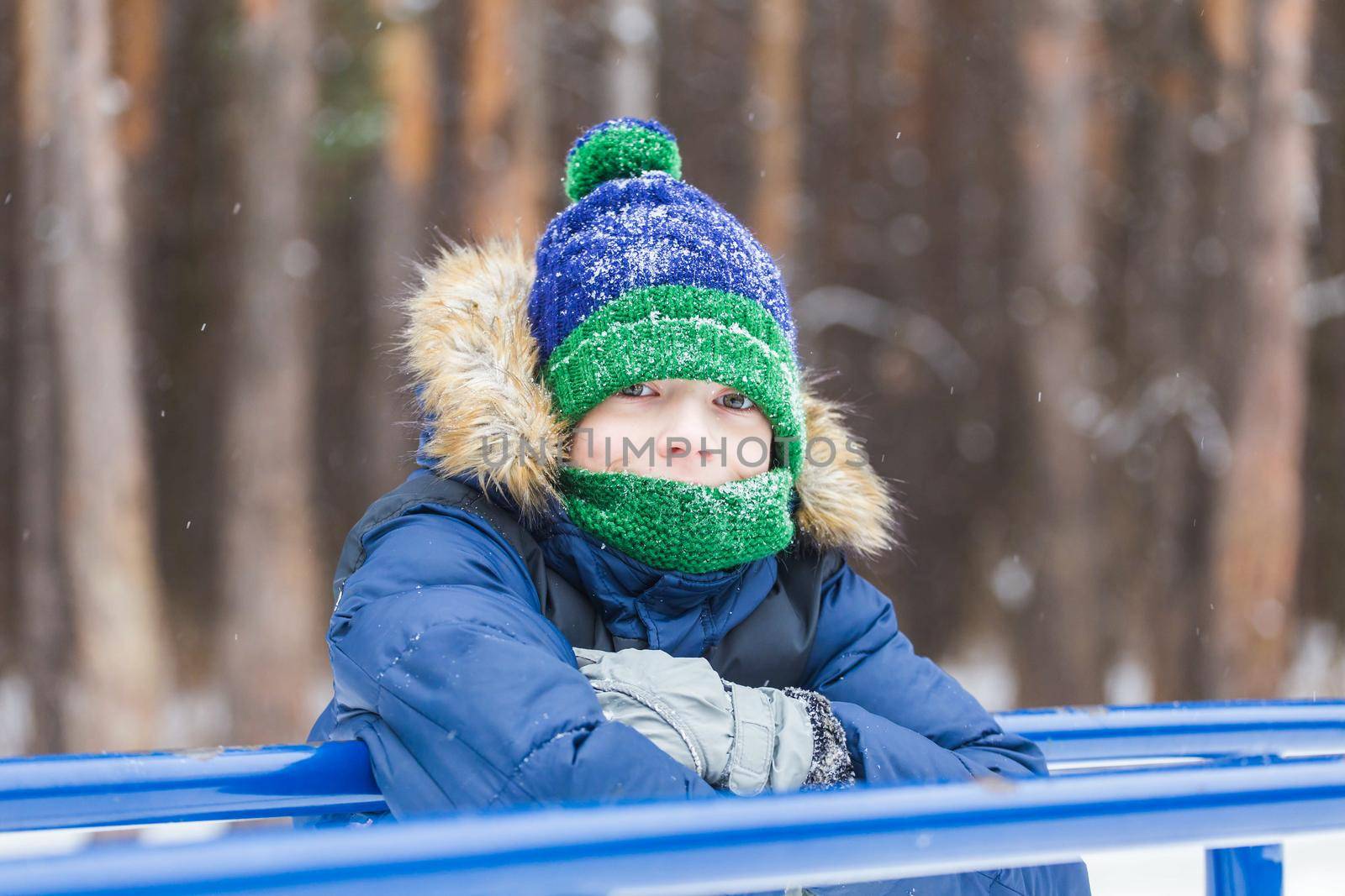 Young boy plays with snow, have fun, smiles. Teenager in winter park. Active lifestyle, winter activity, outdoor winter games, snowballs.