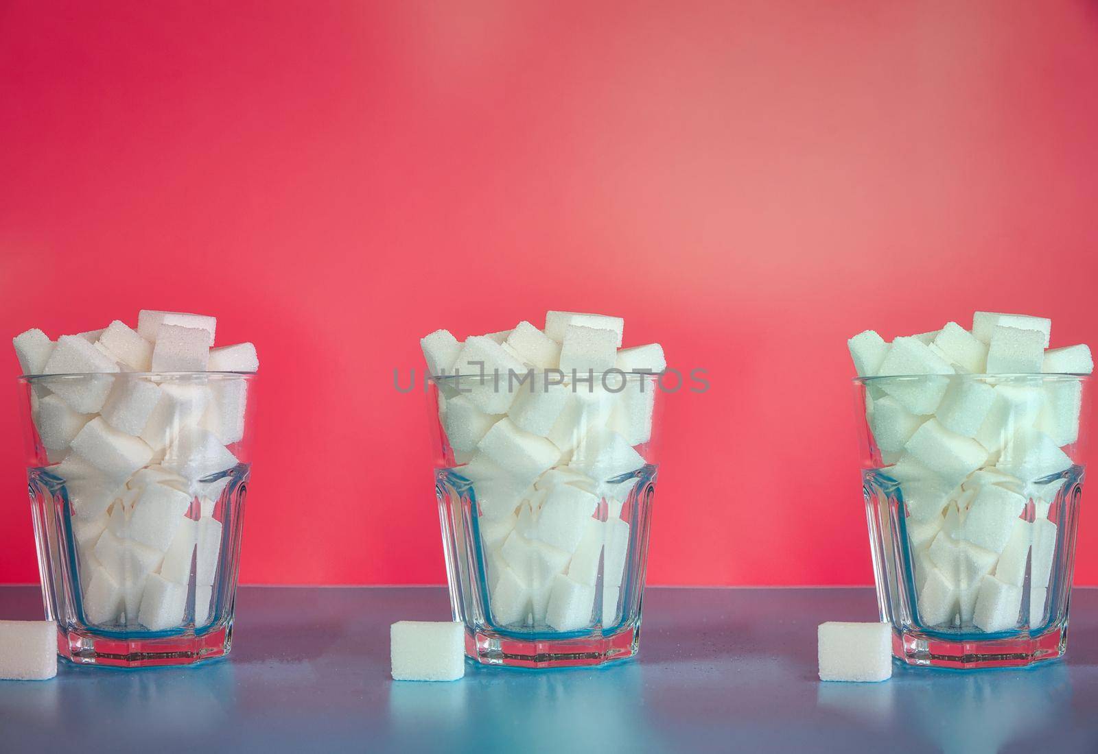 Three Glasses full with sugar cubes on pink background, sugar,unhealthy,sweets,junk food concept background retro modern design pastel colors