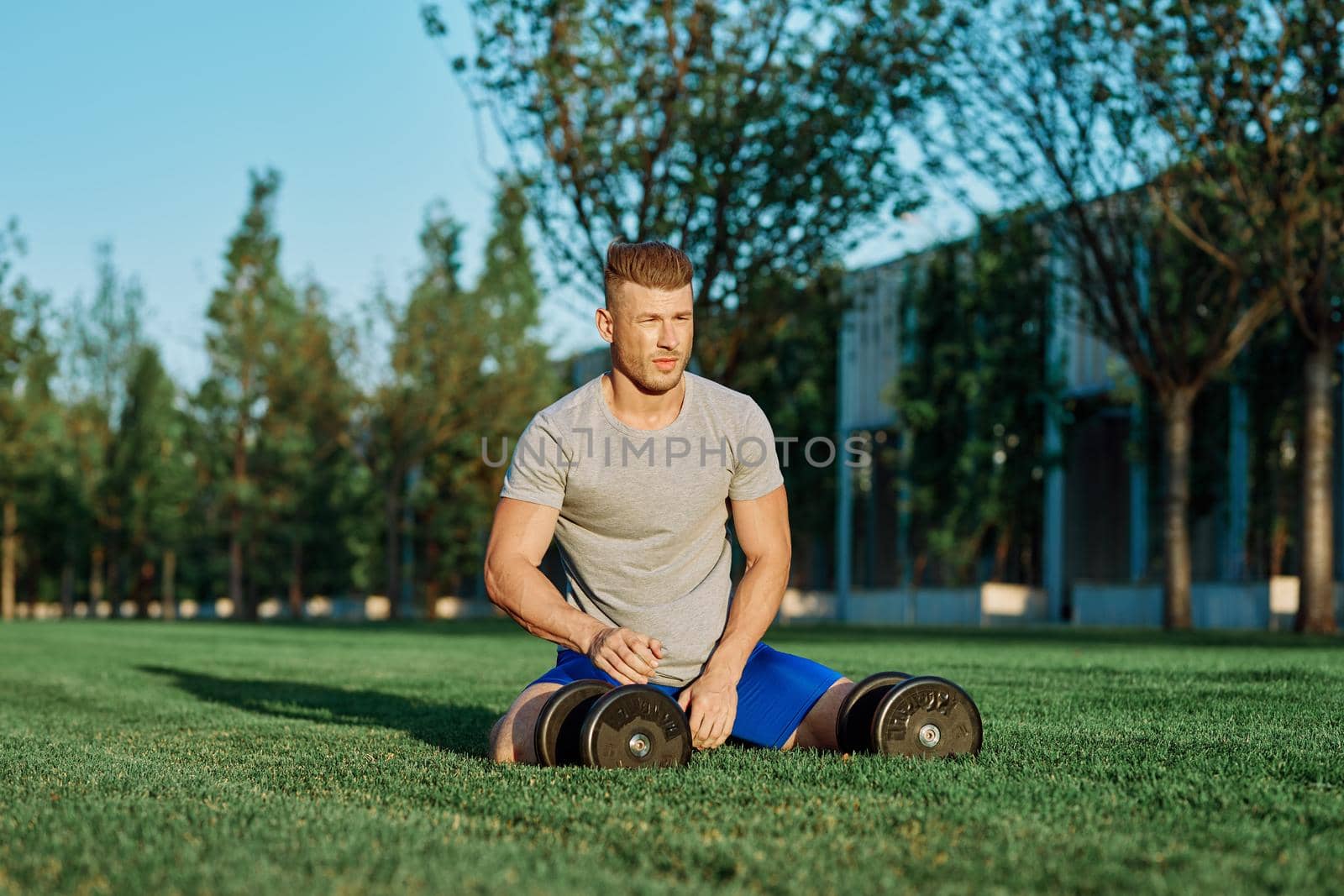 athletic man training with dumbbells in the morning Park by Vichizh